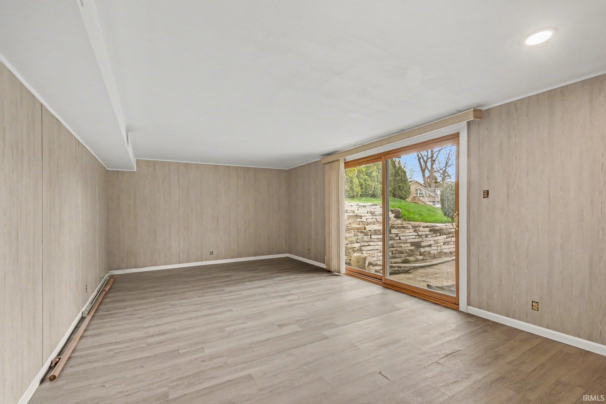 Unfurnished room with light wood finished floors and wooden walls