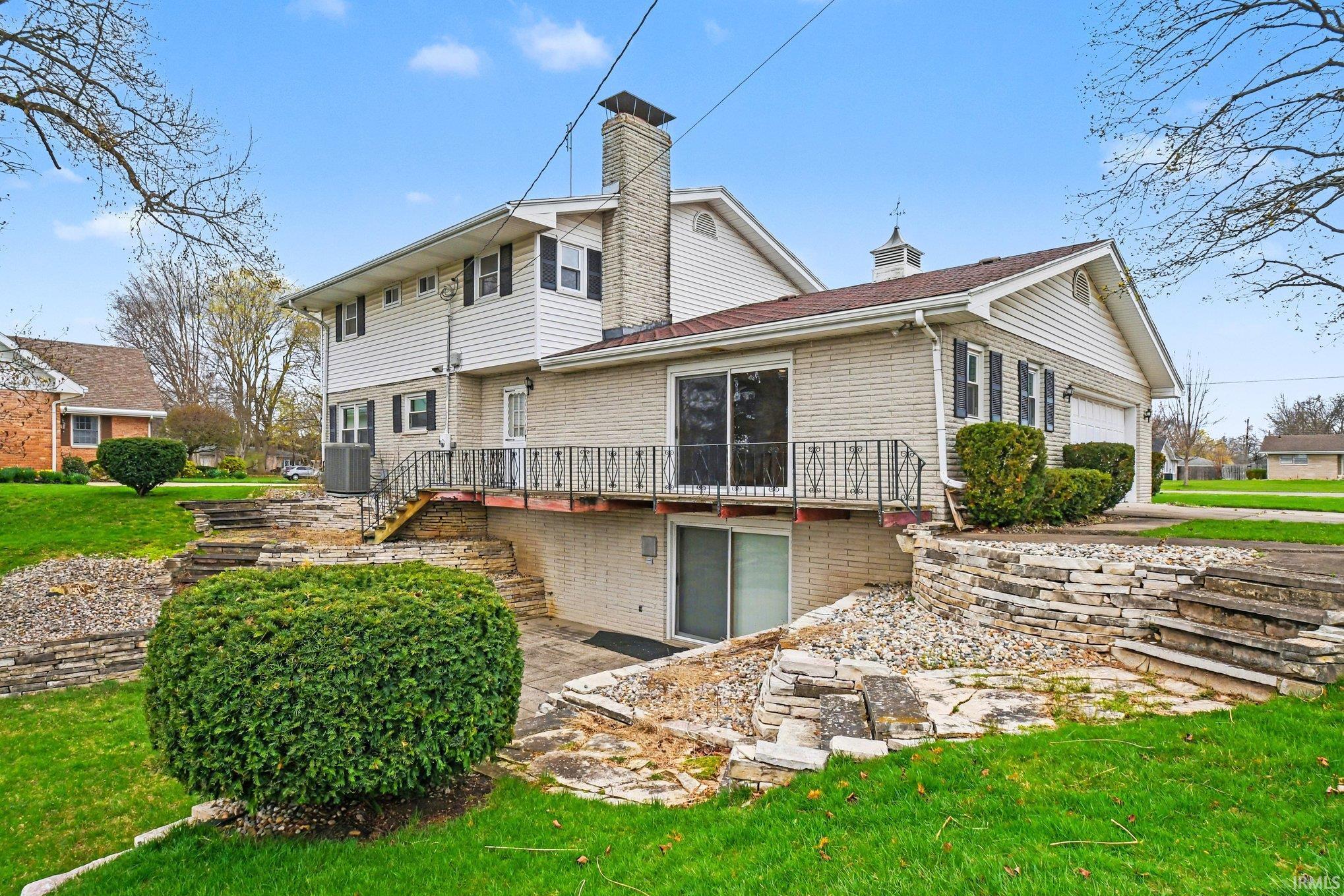 Rear view of house with a chimney, a yard, a patio, and brick siding