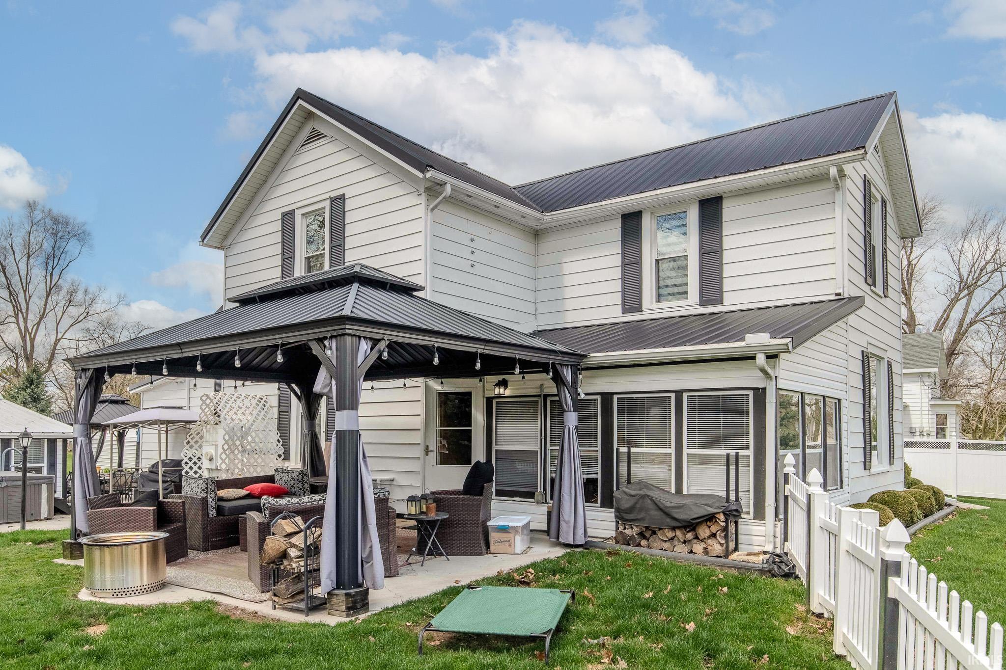 Rear view of property featuring a gazebo, a metal roof, a patio, and outdoor furniture