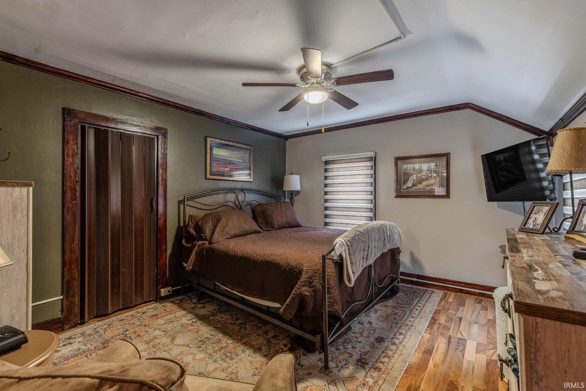 Bedroom featuring light wood finished floors, ornamental molding, and a ceiling fan