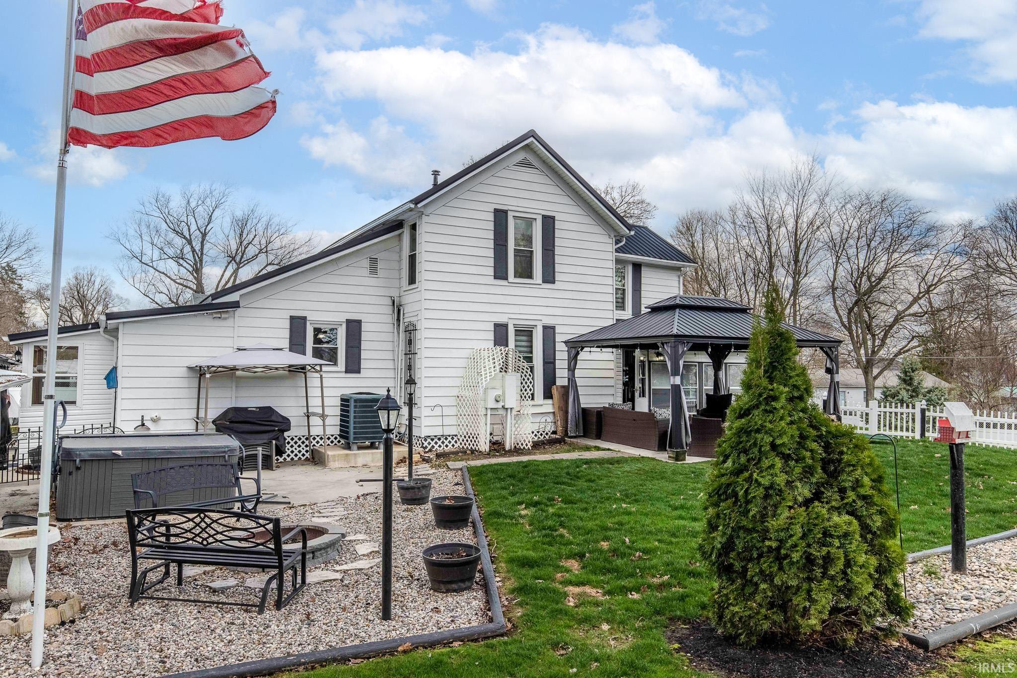Rear view of property with a gazebo, a patio area, and a hot tub