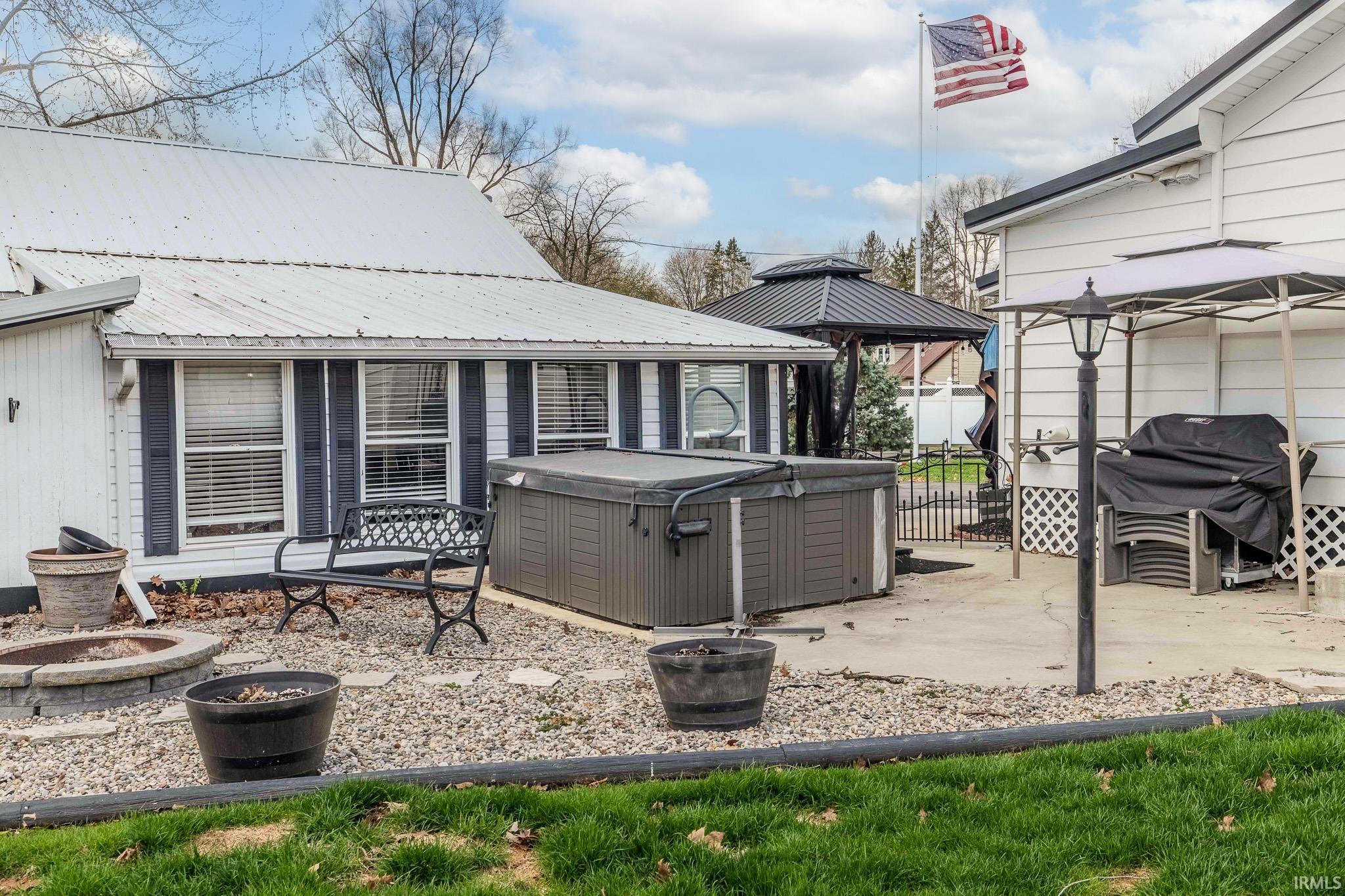 View of patio / terrace with a gazebo, an outdoor fire pit, grilling area, and a hot tub