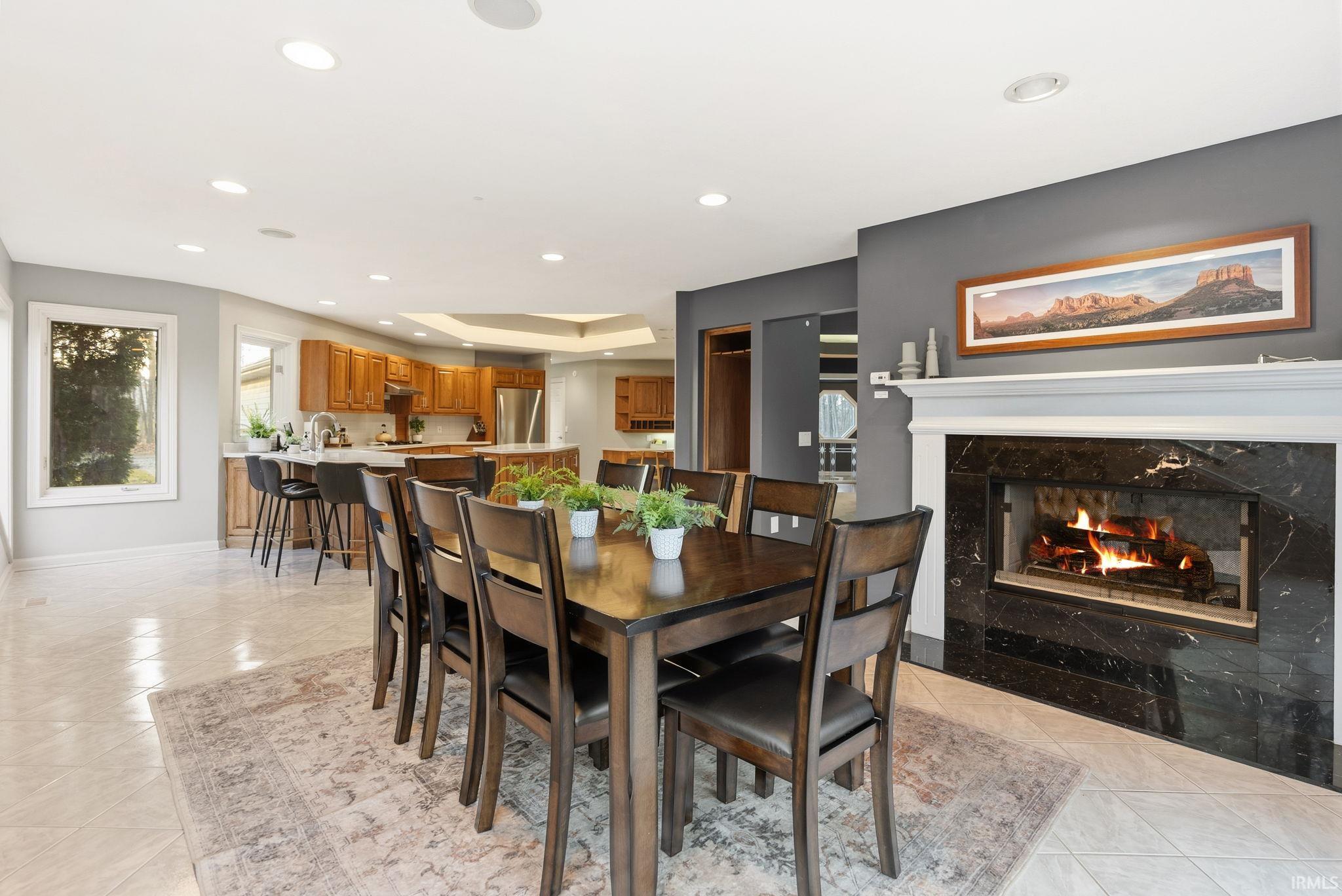 Dining room with a premium fireplace, recessed lighting, light tile patterned floors, and a tray ceiling