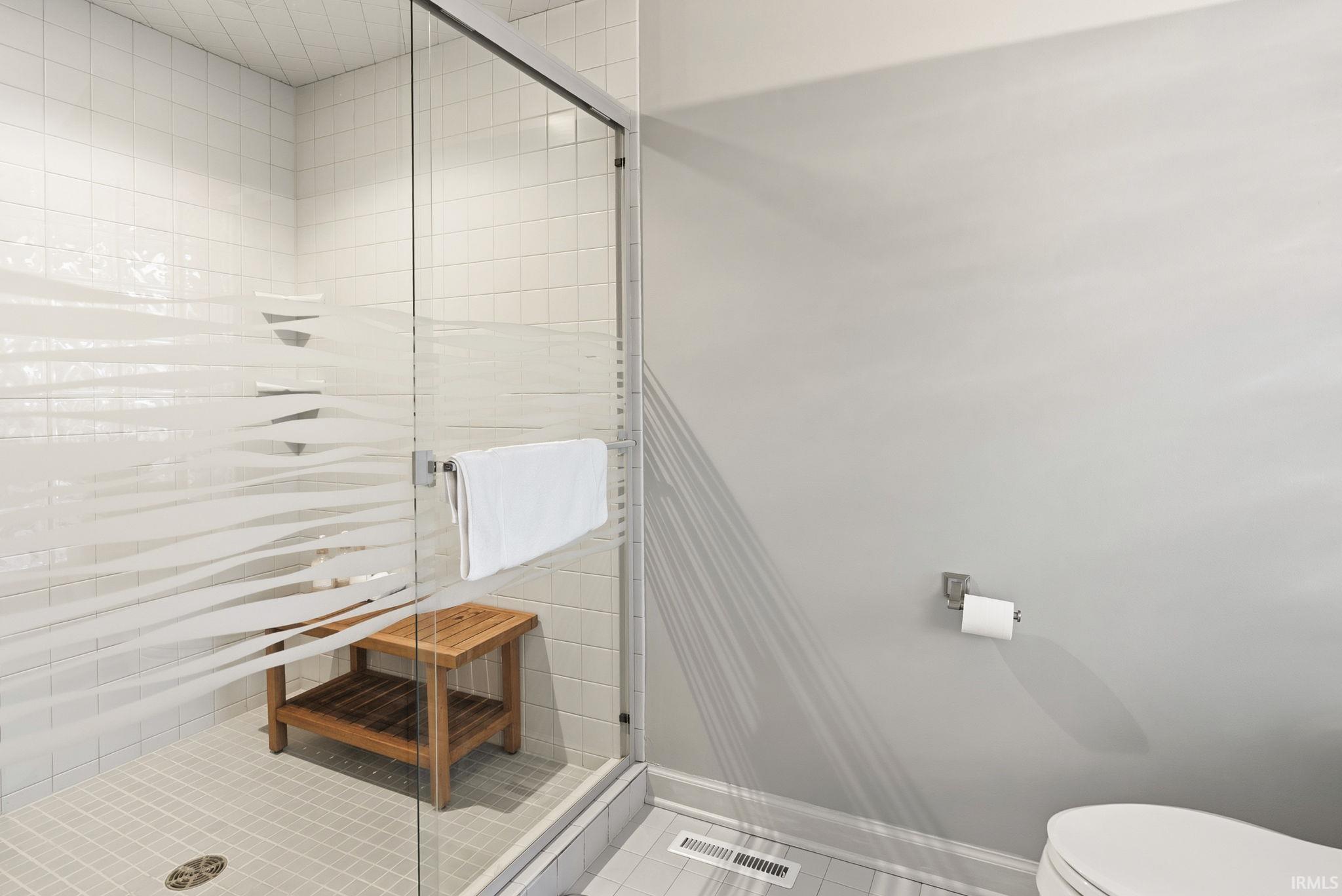 Full bath featuring a stall shower and light tile patterned flooring