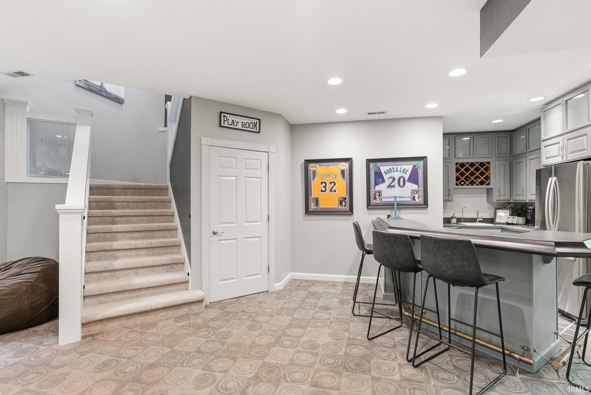 Indoor wet bar with gray cabinets, freestanding refrigerator, glass insert cabinets, recessed lighting, and light colored carpet