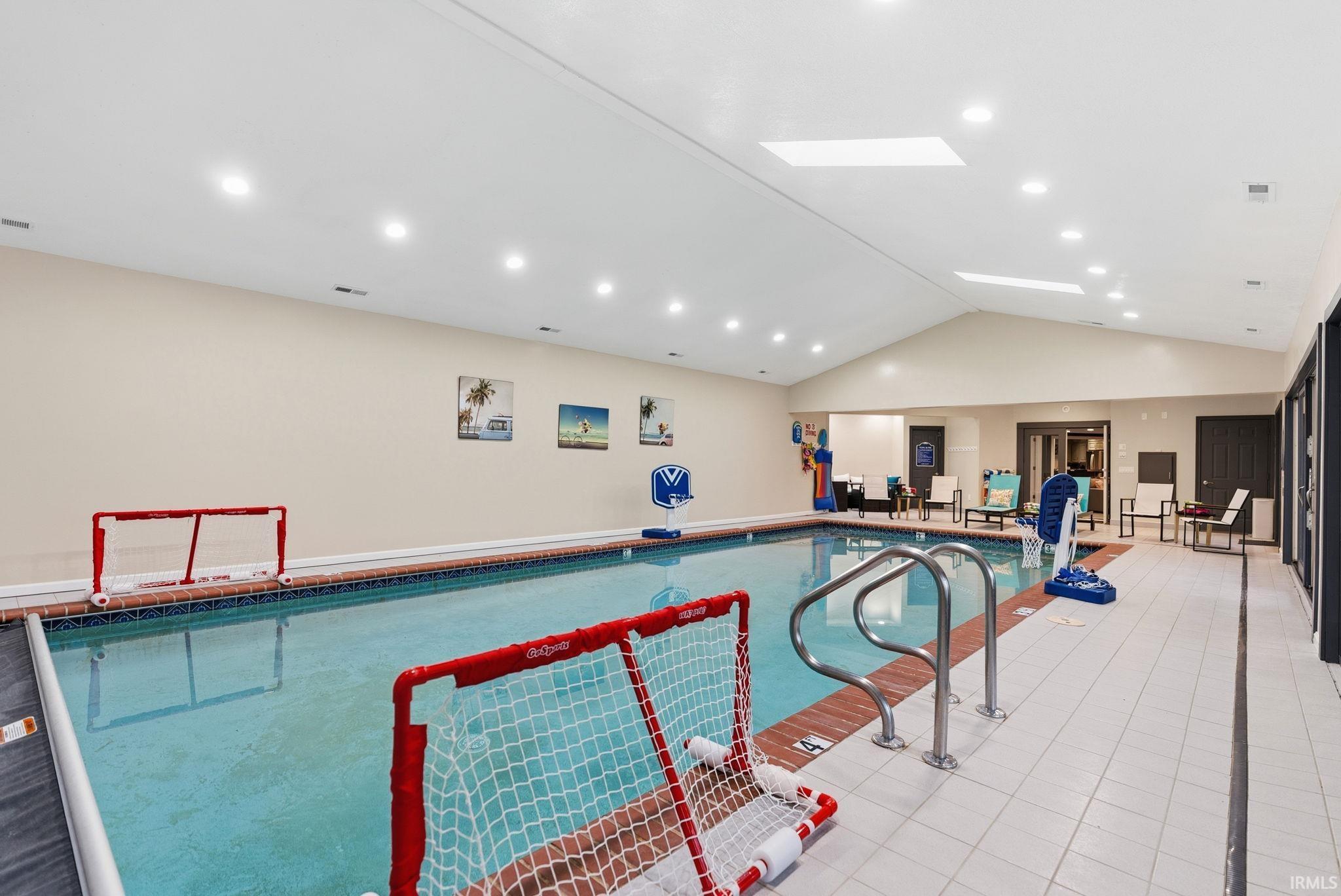 Indoor community pool featuring a skylight