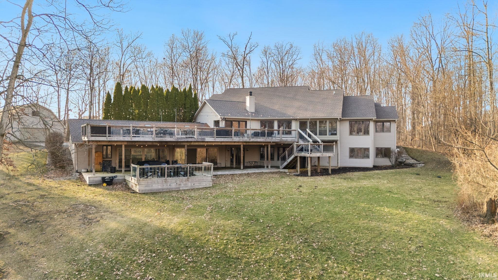 Back of property featuring a wooden deck, a yard, and a chimney