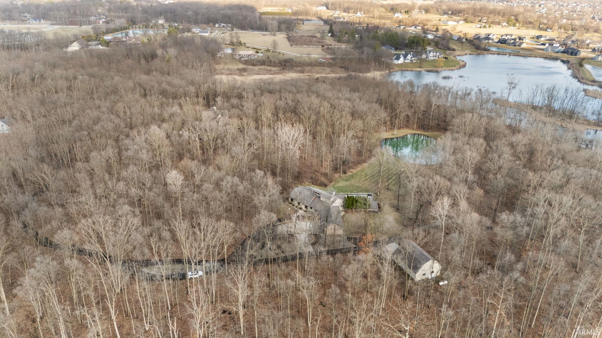 Aerial view of property and surrounding area with a large body of water and a forest