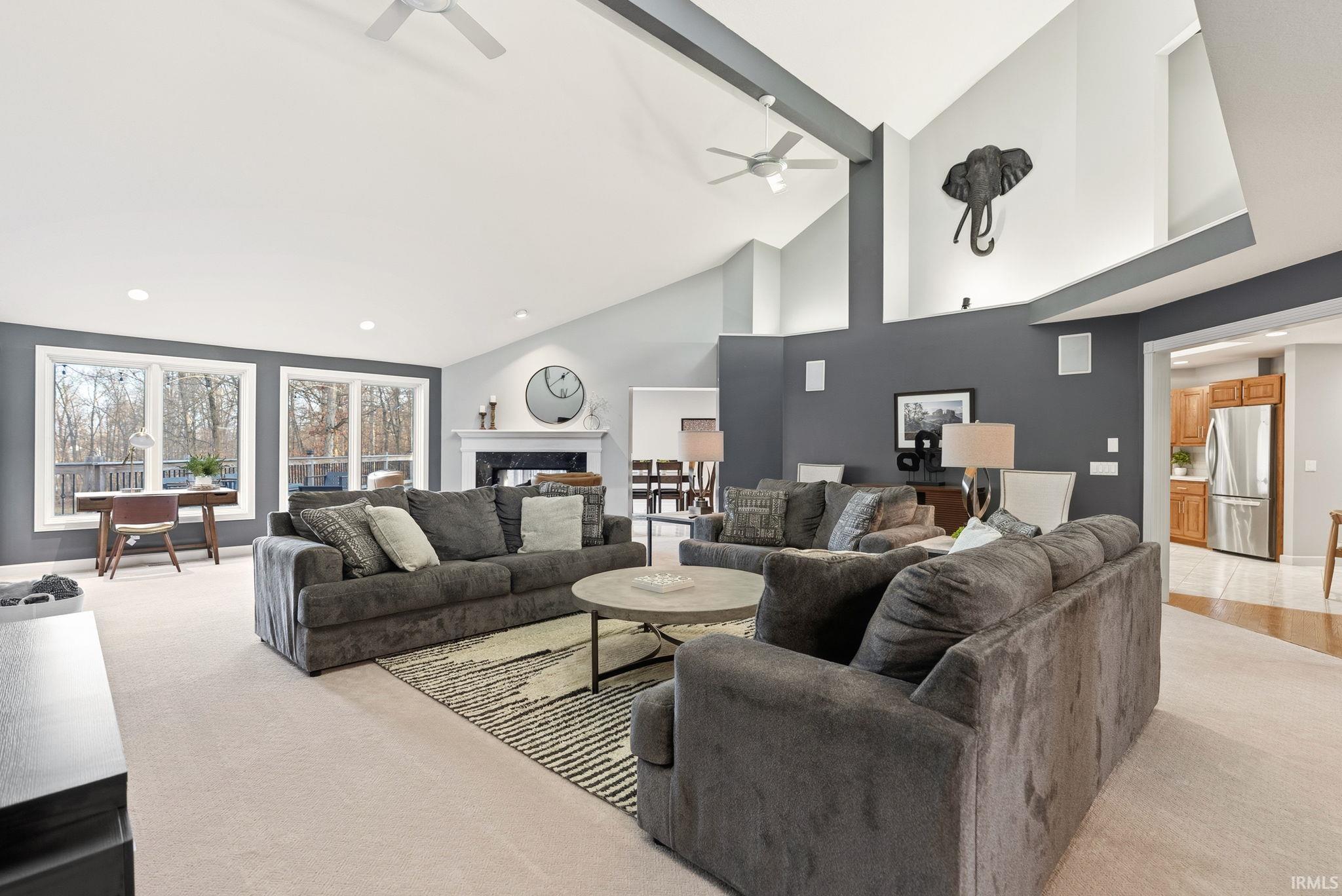 Living area featuring lofted ceiling, light carpet, a high end fireplace, a ceiling fan, and recessed lighting