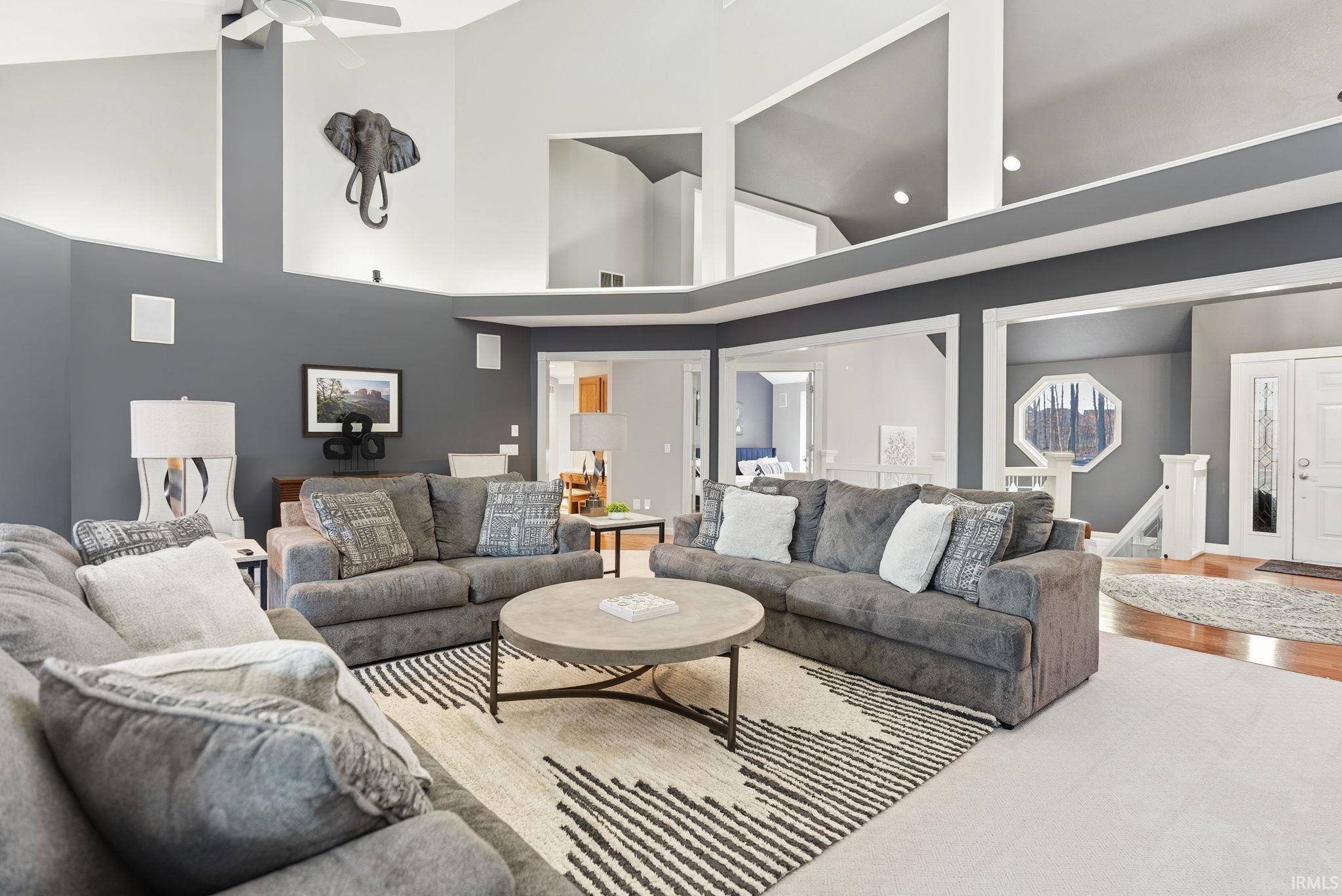 Living room with ceiling fan, wood finished floors, and vaulted ceiling