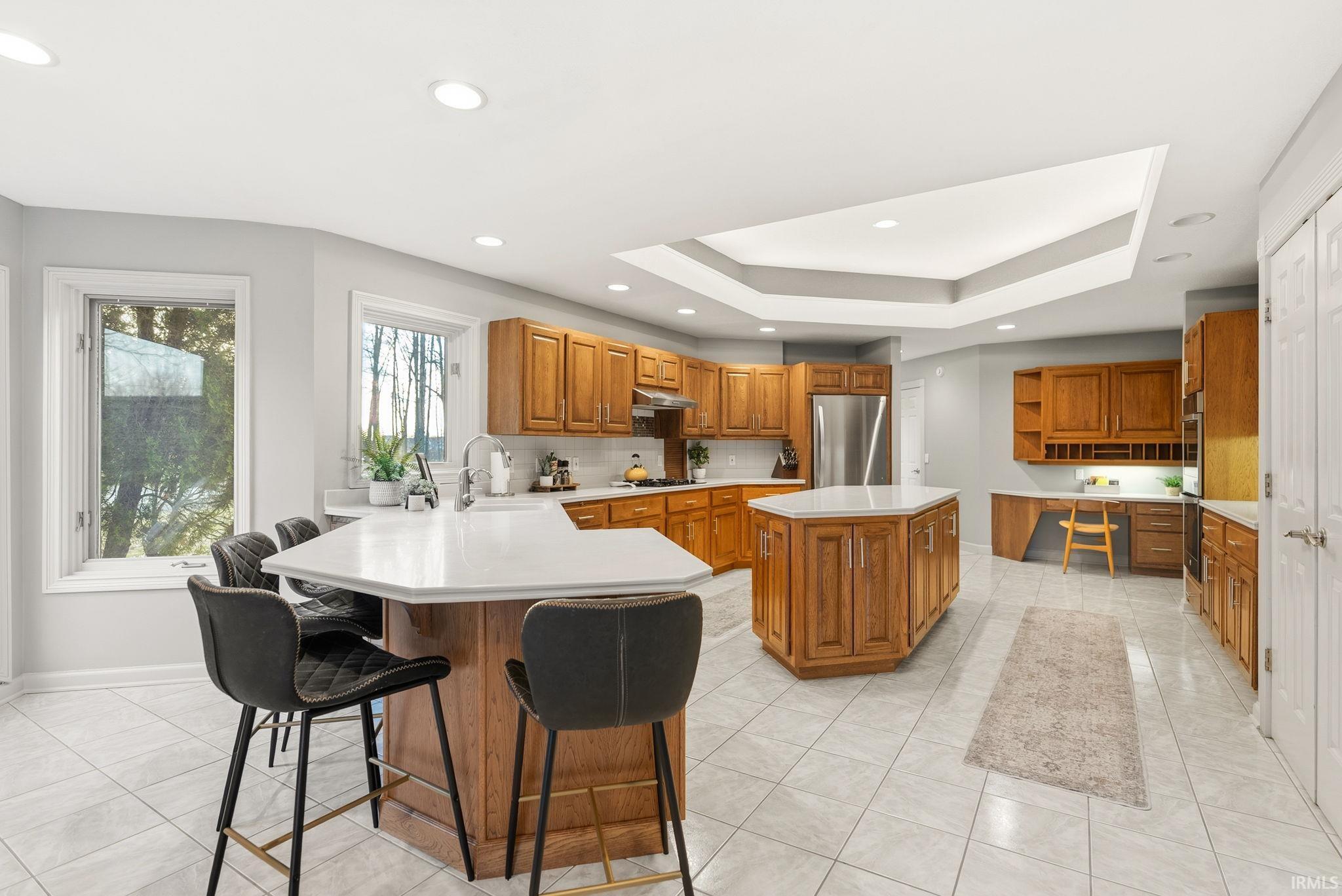 Kitchen featuring wood finish cabinetry, open shelves, a center island, a peninsula, and light countertops