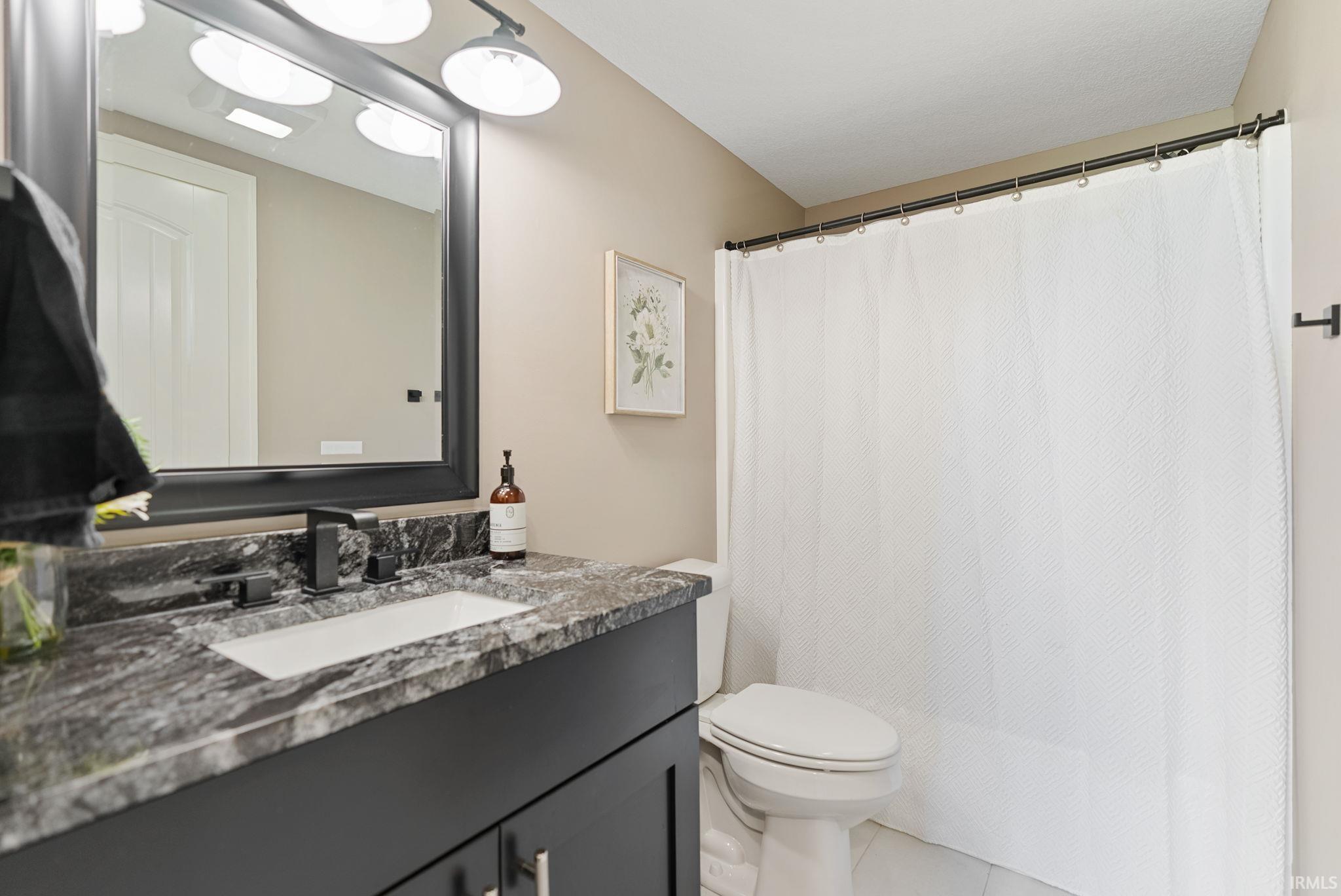 Bathroom featuring vanity, a shower with shower curtain, and tile patterned flooring