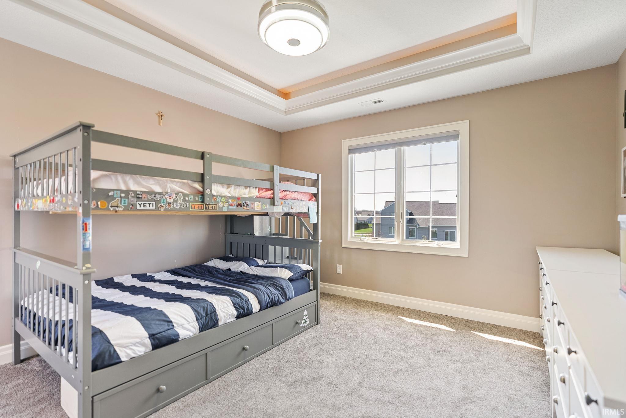 Bedroom with light carpet and a raised ceiling