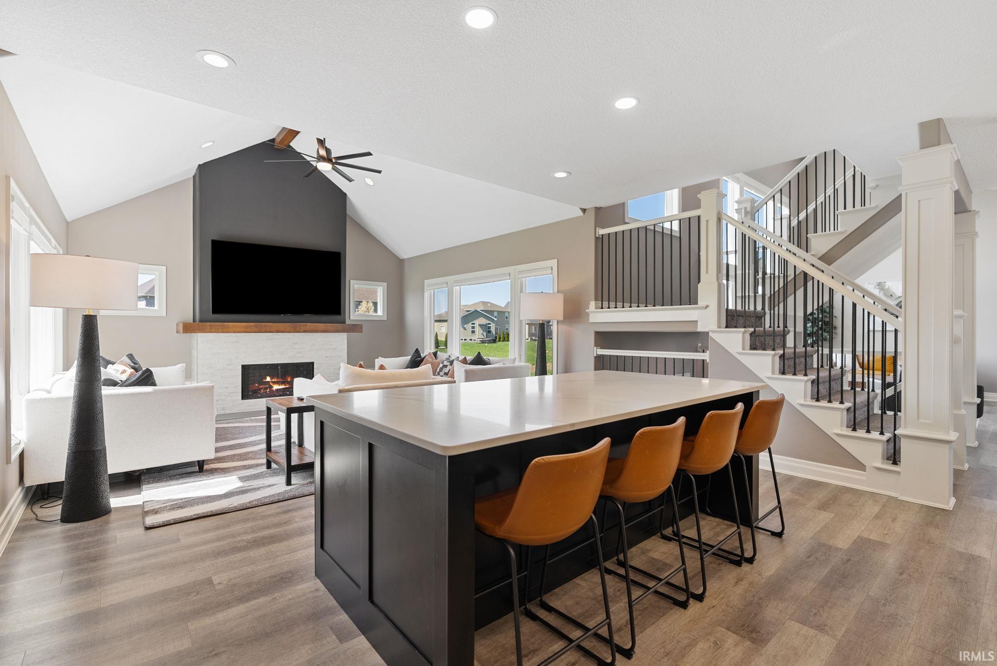 Kitchen with a center island, a lit fireplace, light wood finished floors, open floor plan, and a high ceiling