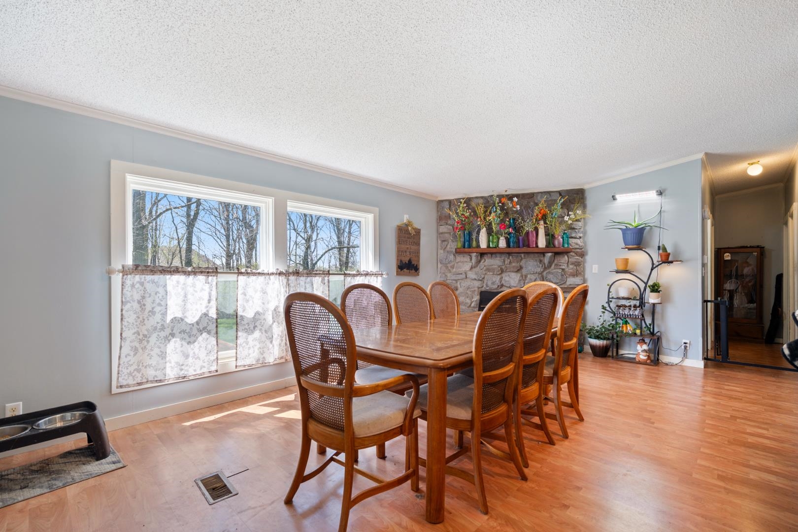 Dining room with light wood-type flooring, a fireplace, a textured ceiling, and ornamental molding