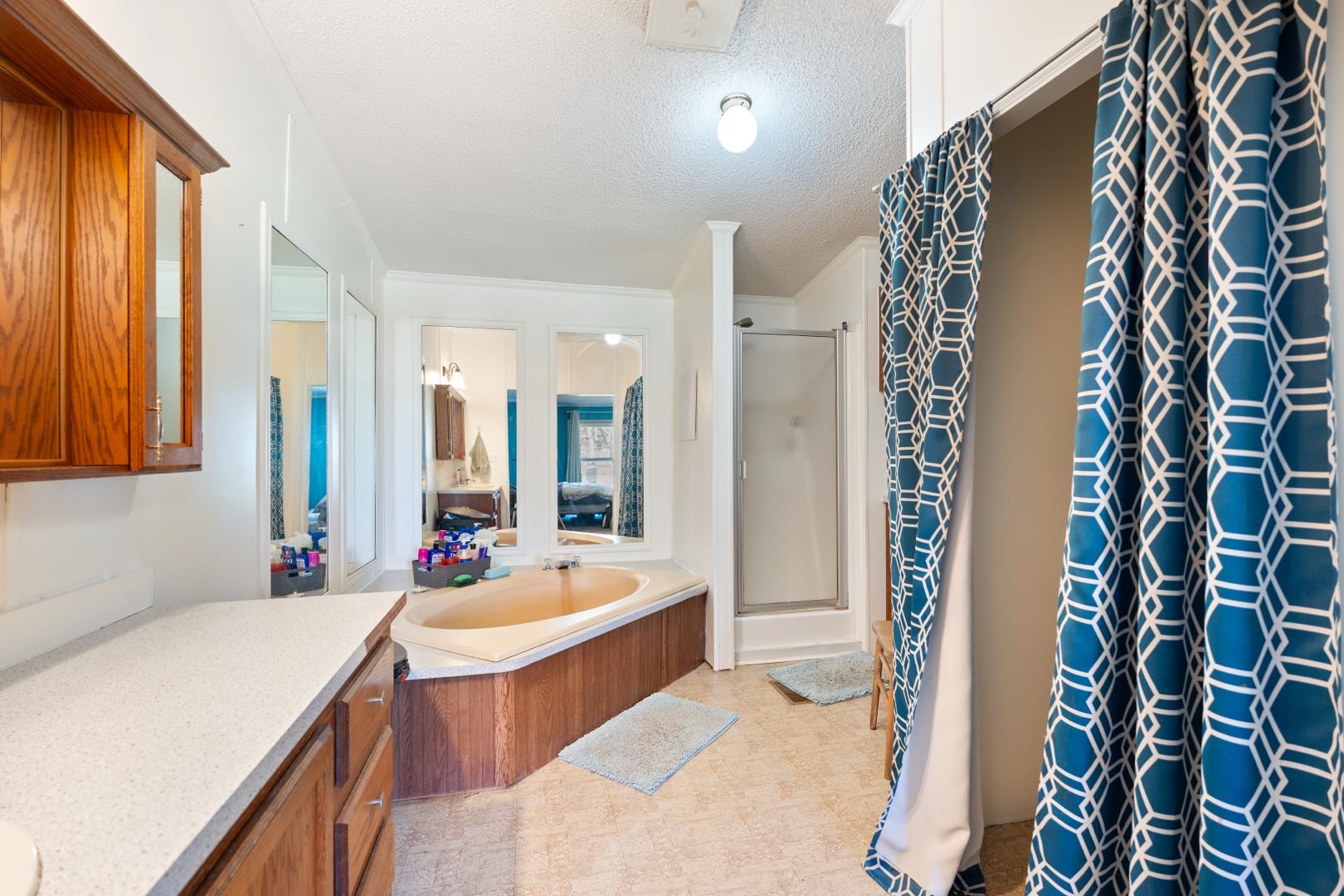 Full bath with a textured ceiling, a shower stall, a bath, vanity, and light floors
