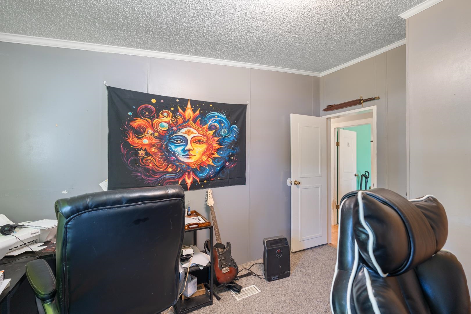 Office area with crown molding, a textured ceiling, carpet, and a decorative wall