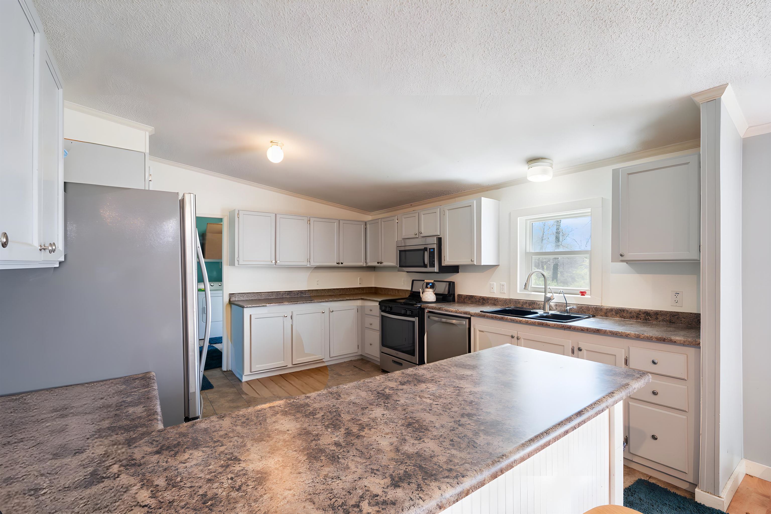 Kitchen with stainless steel appliances, a peninsula, vaulted ceiling, and crown molding