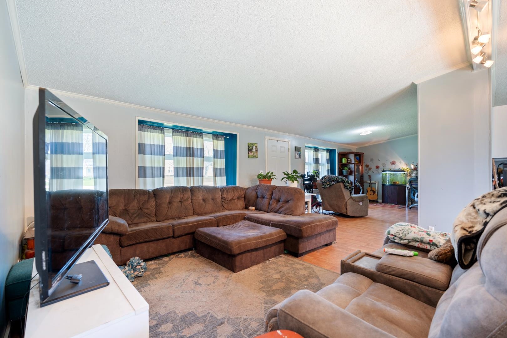 Living area featuring wood finished floors, ornamental molding, and a textured ceiling