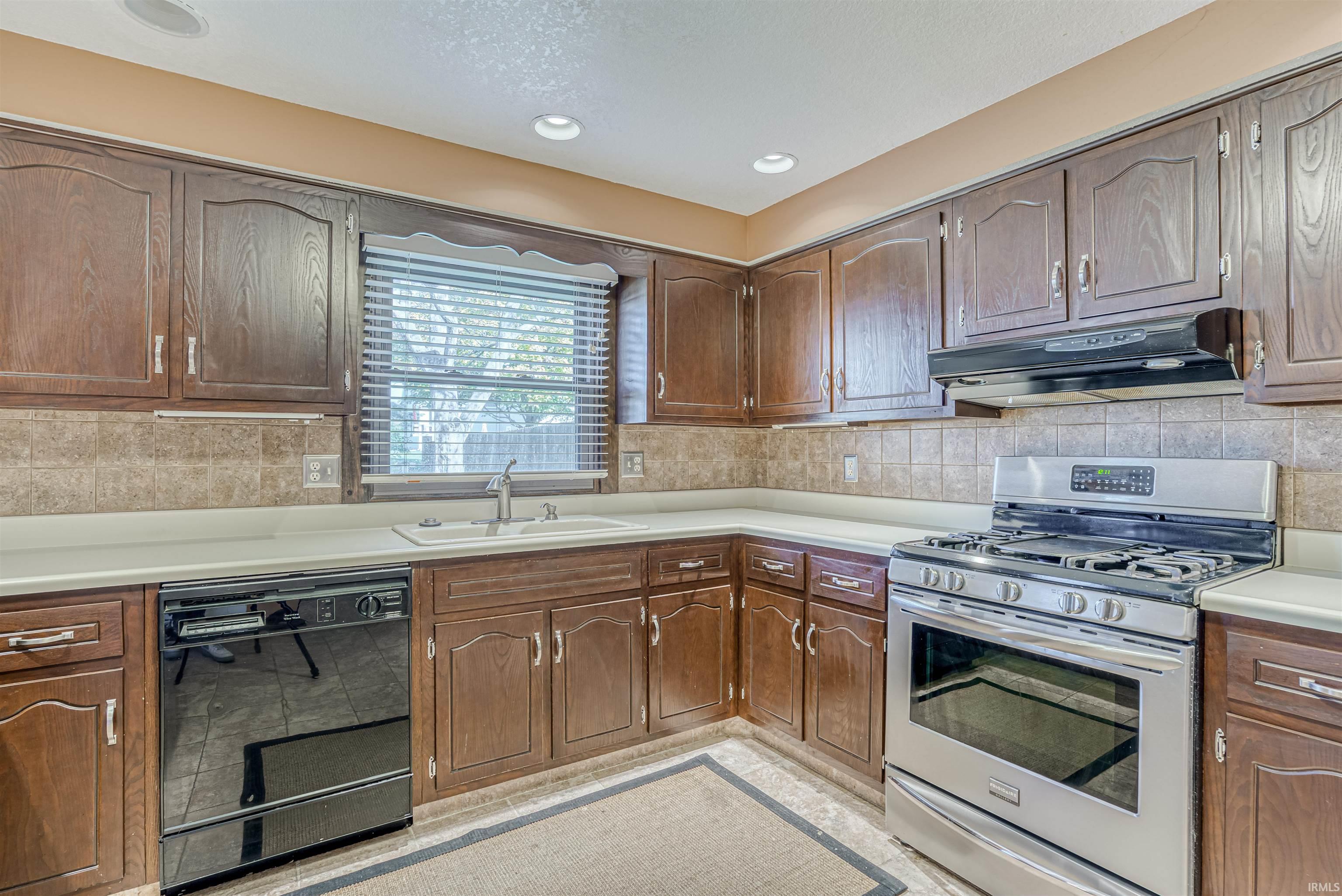 Kitchen featuring stainless steel gas range, dishwasher, light countertops, decorative backsplash, and recessed lighting