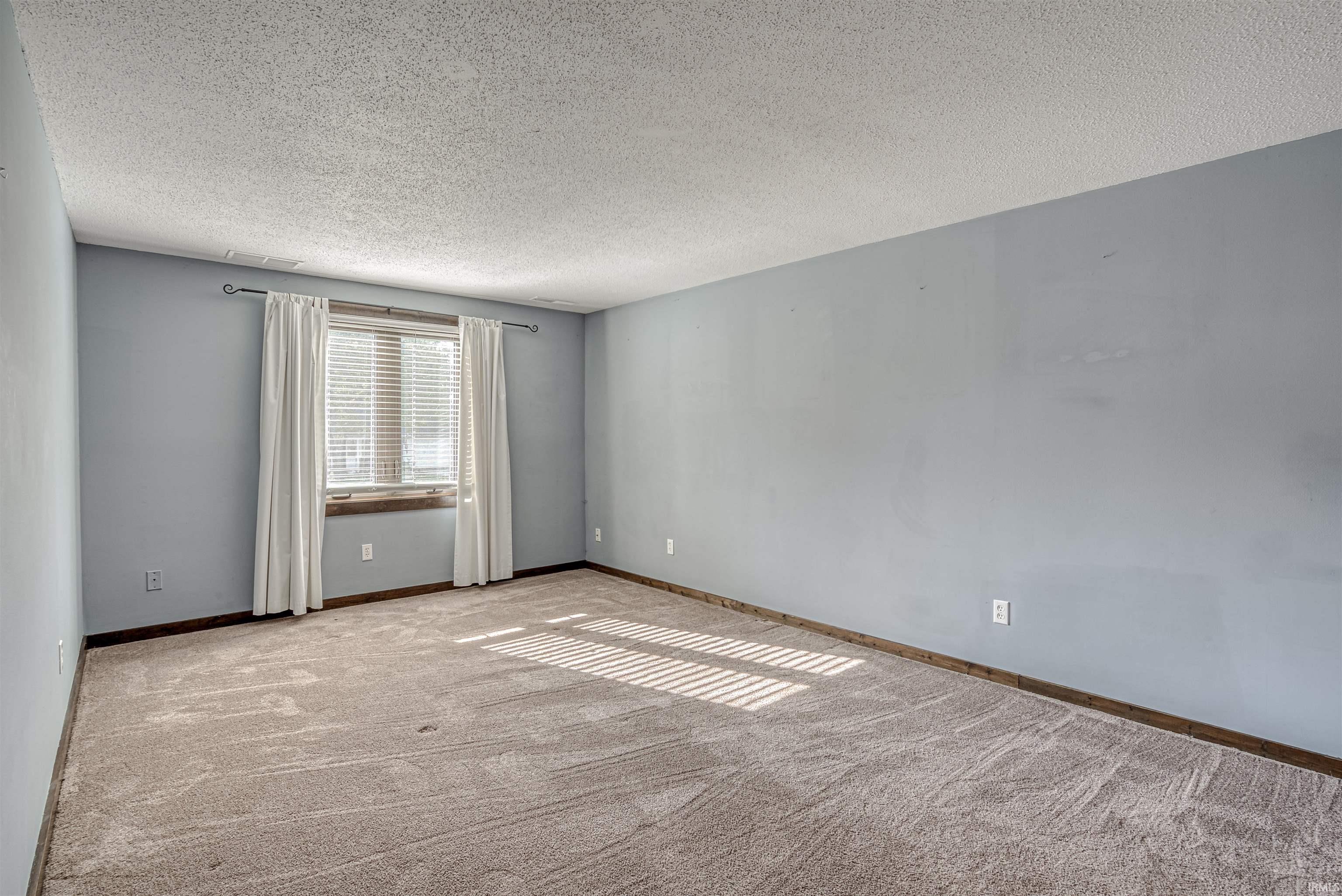 Spare room featuring a textured ceiling and light colored carpet