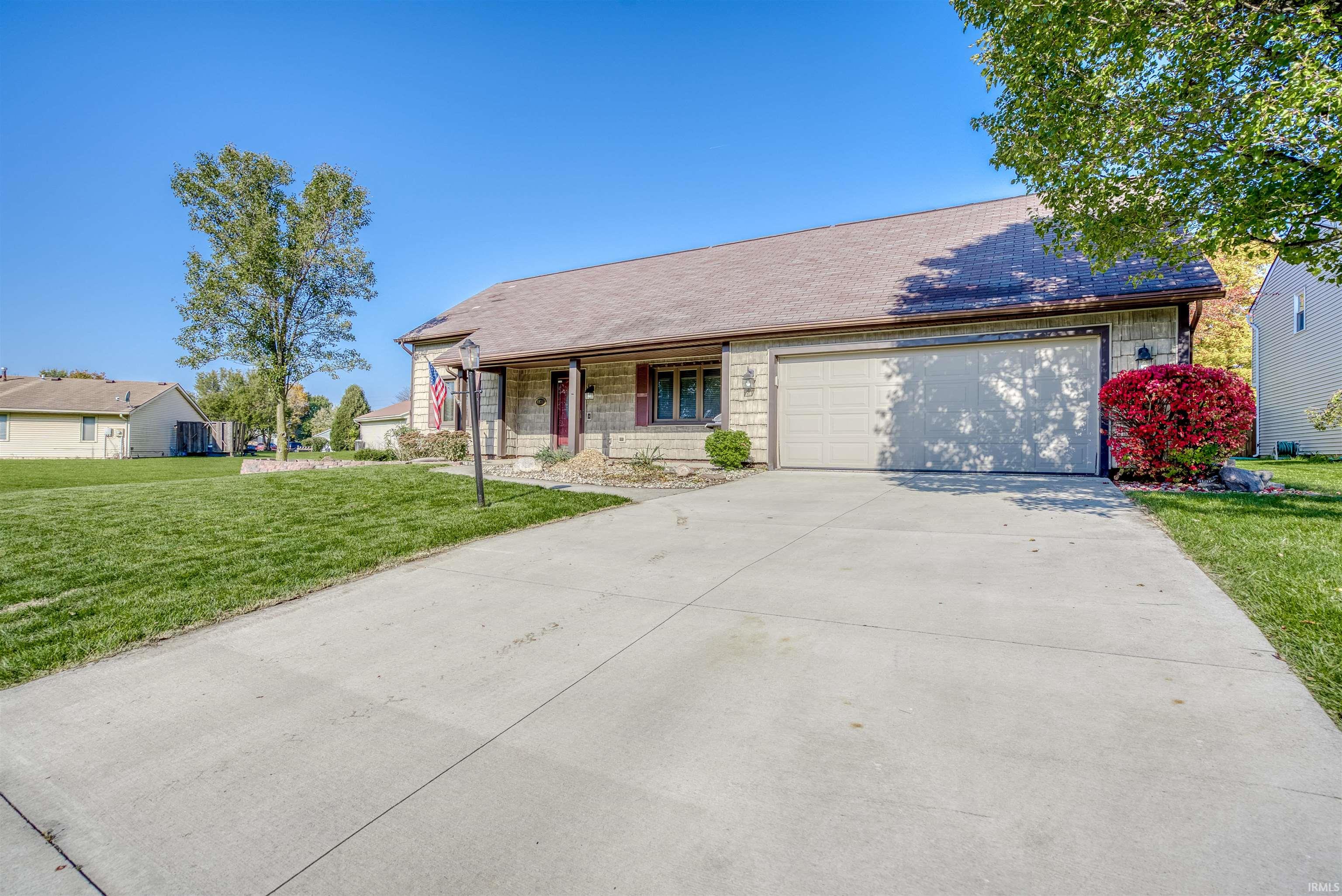 View of front of home with a front lawn, driveway, a garage, and covered porch