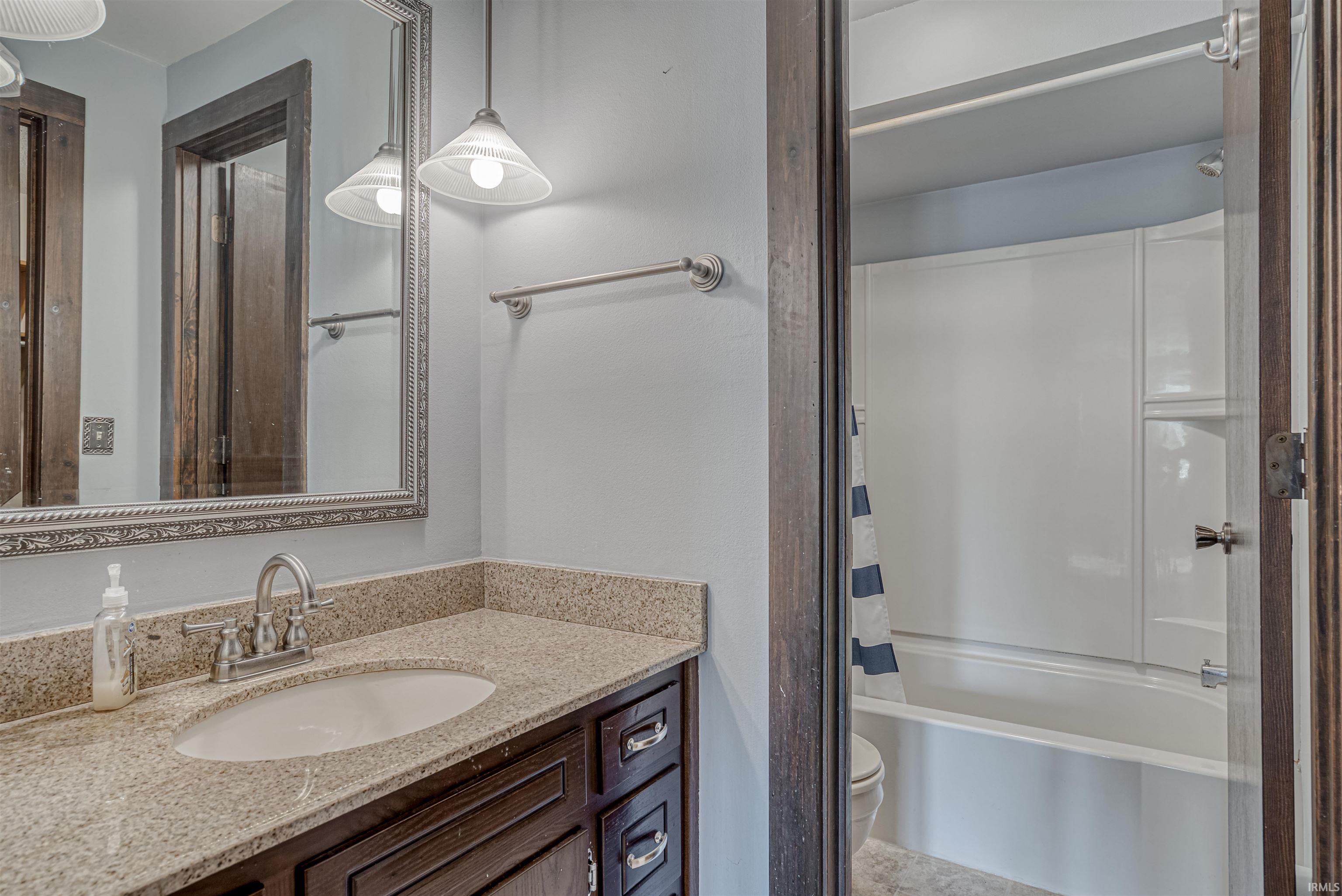 Bathroom featuring vanity and shower / bath combination with curtain