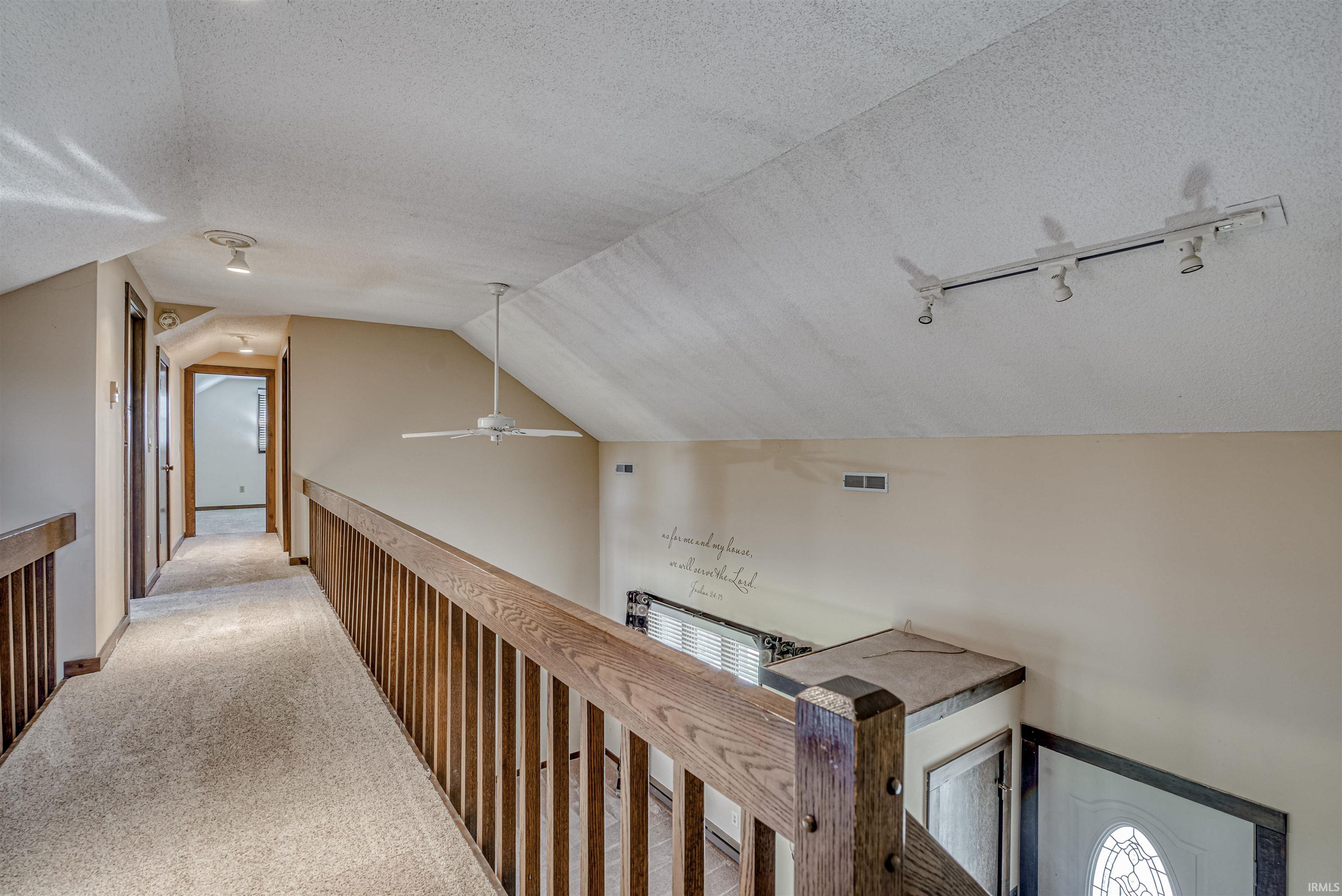 Hallway with carpet floors and an upstairs landing