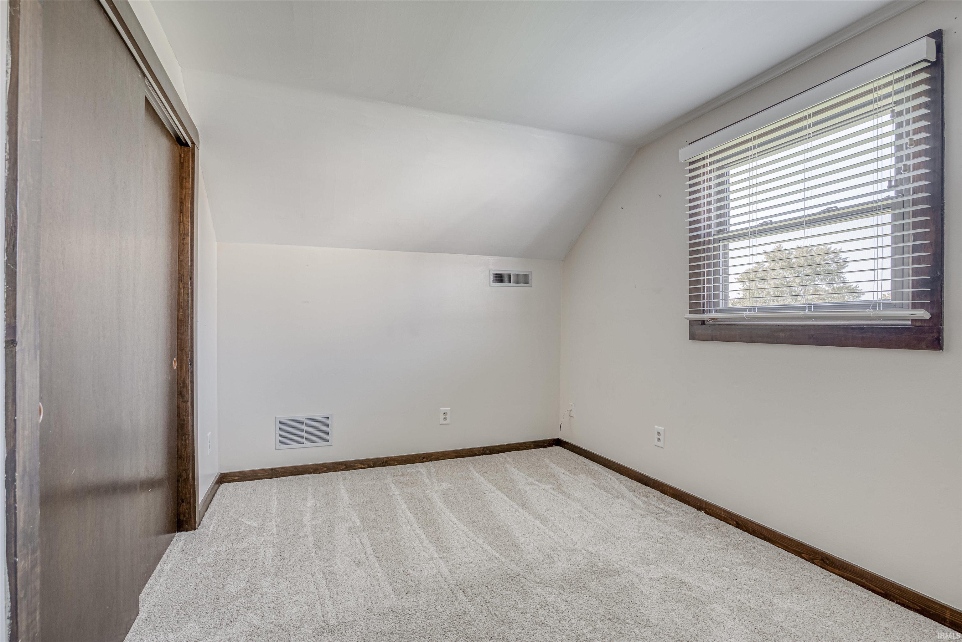 Additional living space featuring light carpet and lofted ceiling