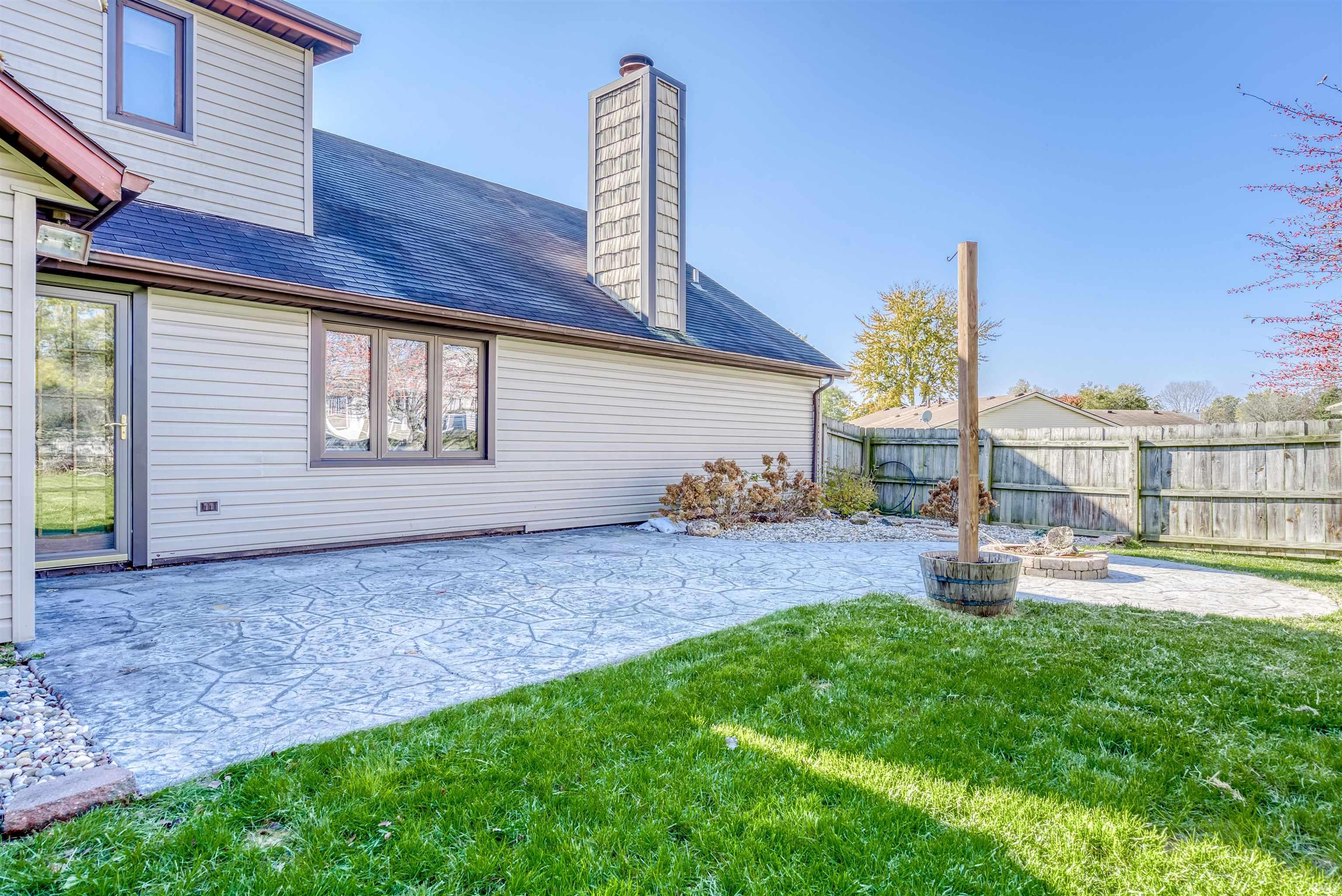 Rear view of property featuring a patio area, a chimney, a fire pit, roof with shingles, and a fenced backyard