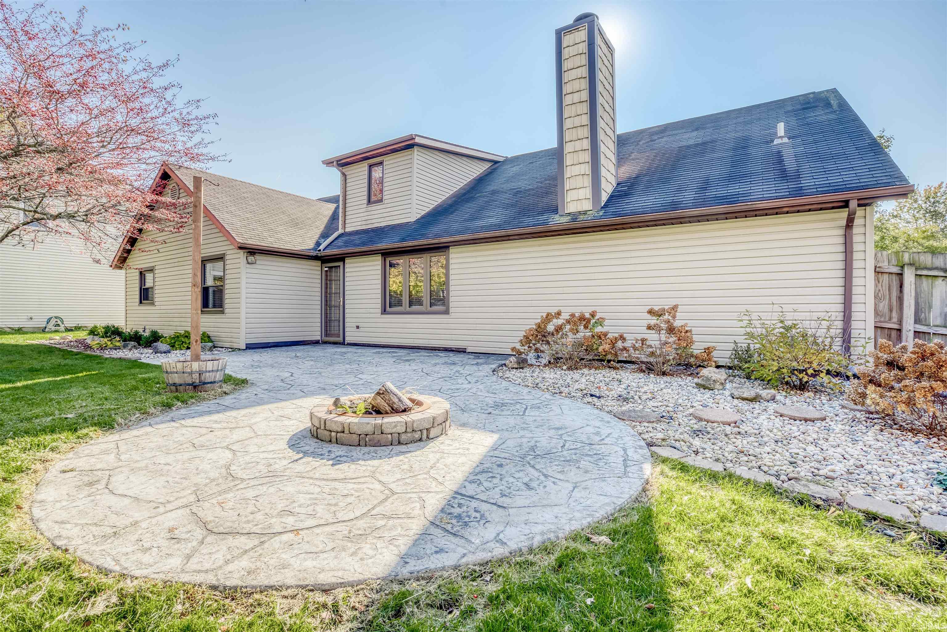 Rear view of property with a patio area, an outdoor fire pit, roof with shingles, a chimney, and a yard