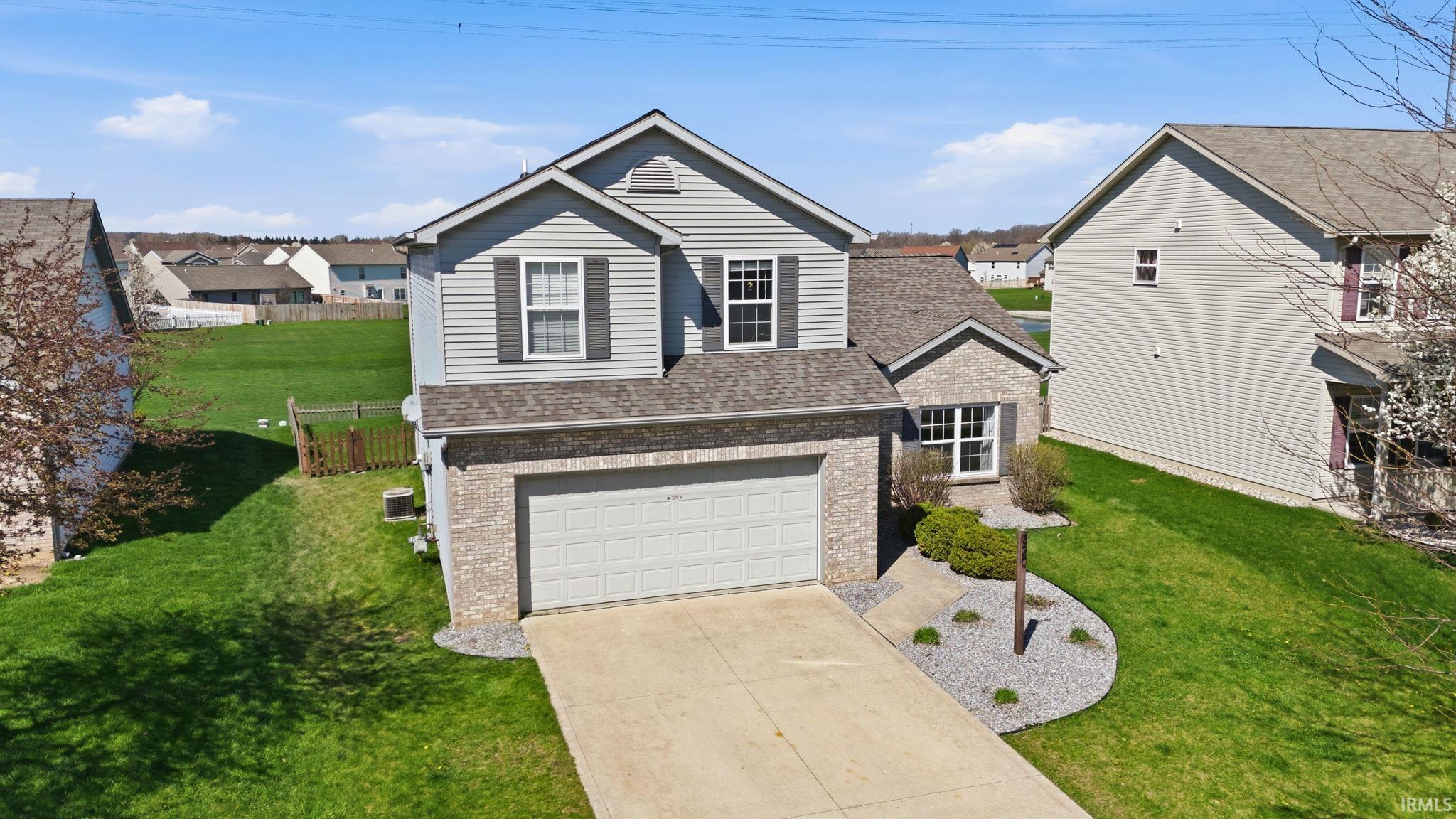 Traditional-style home with driveway, roof with shingles, brick siding, an attached garage, and a residential view