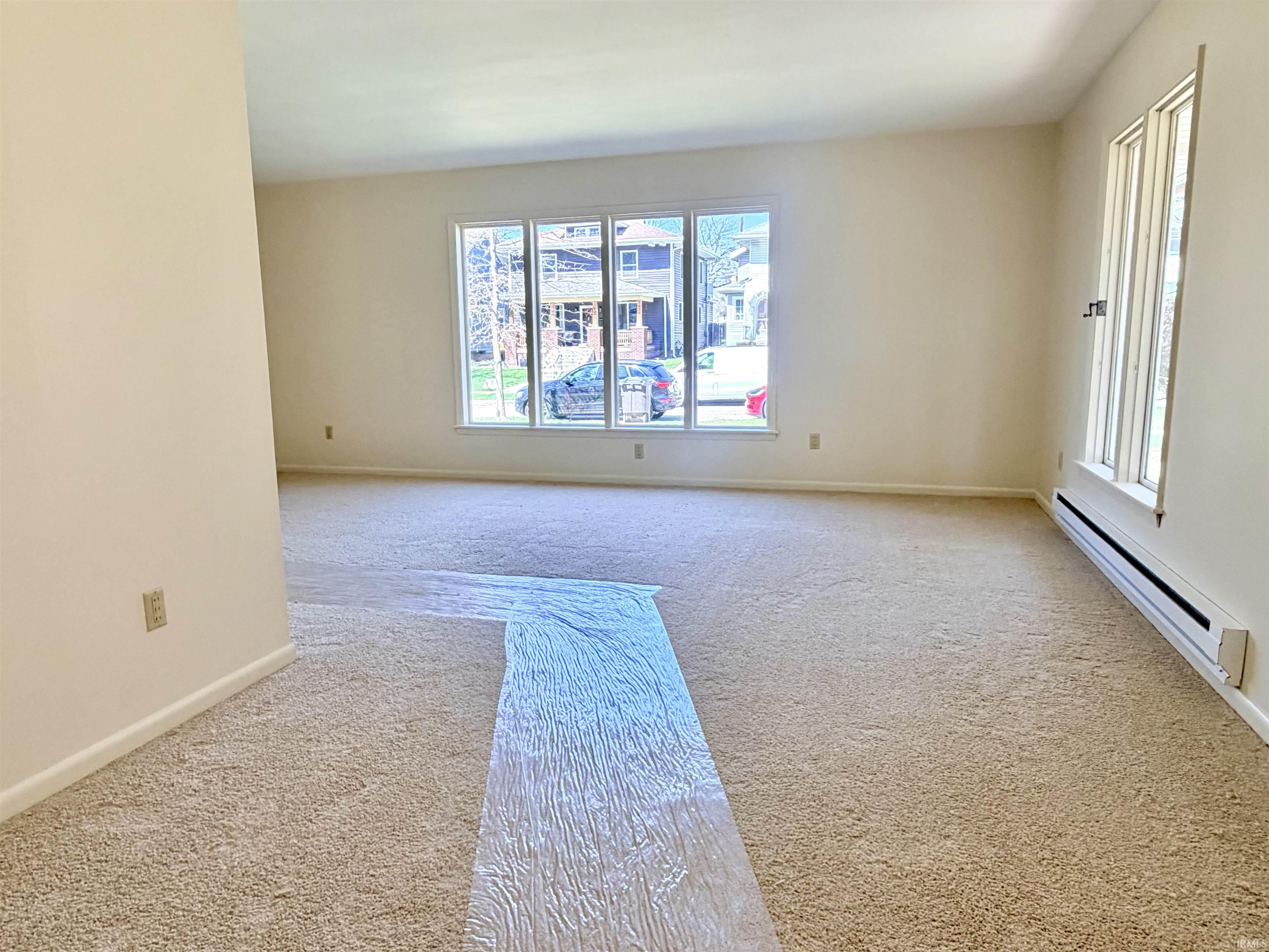 Spare room with a baseboard heating unit and carpet floors
