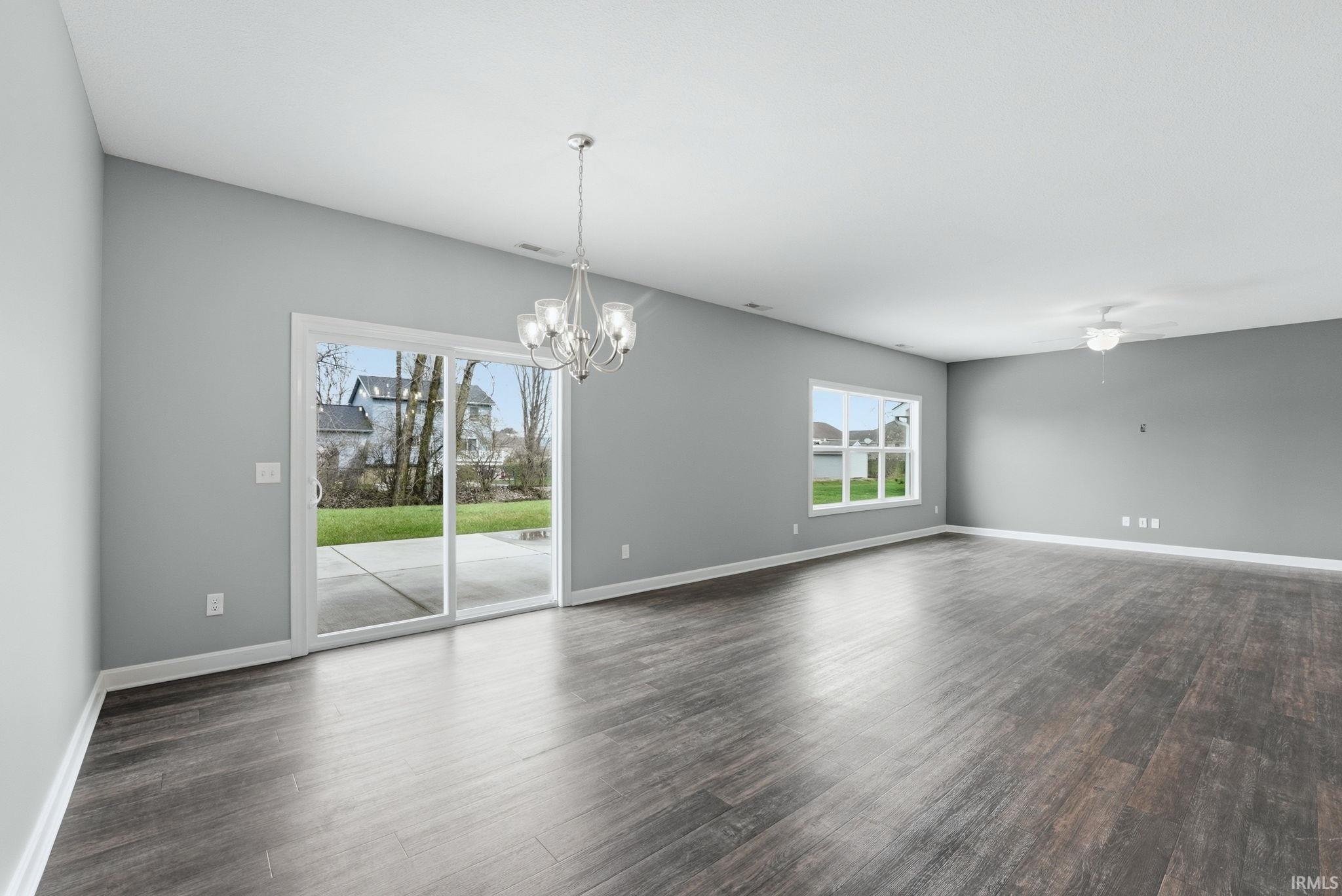 Unfurnished room featuring dark wood finished floors, hanging lights, and a ceiling fan