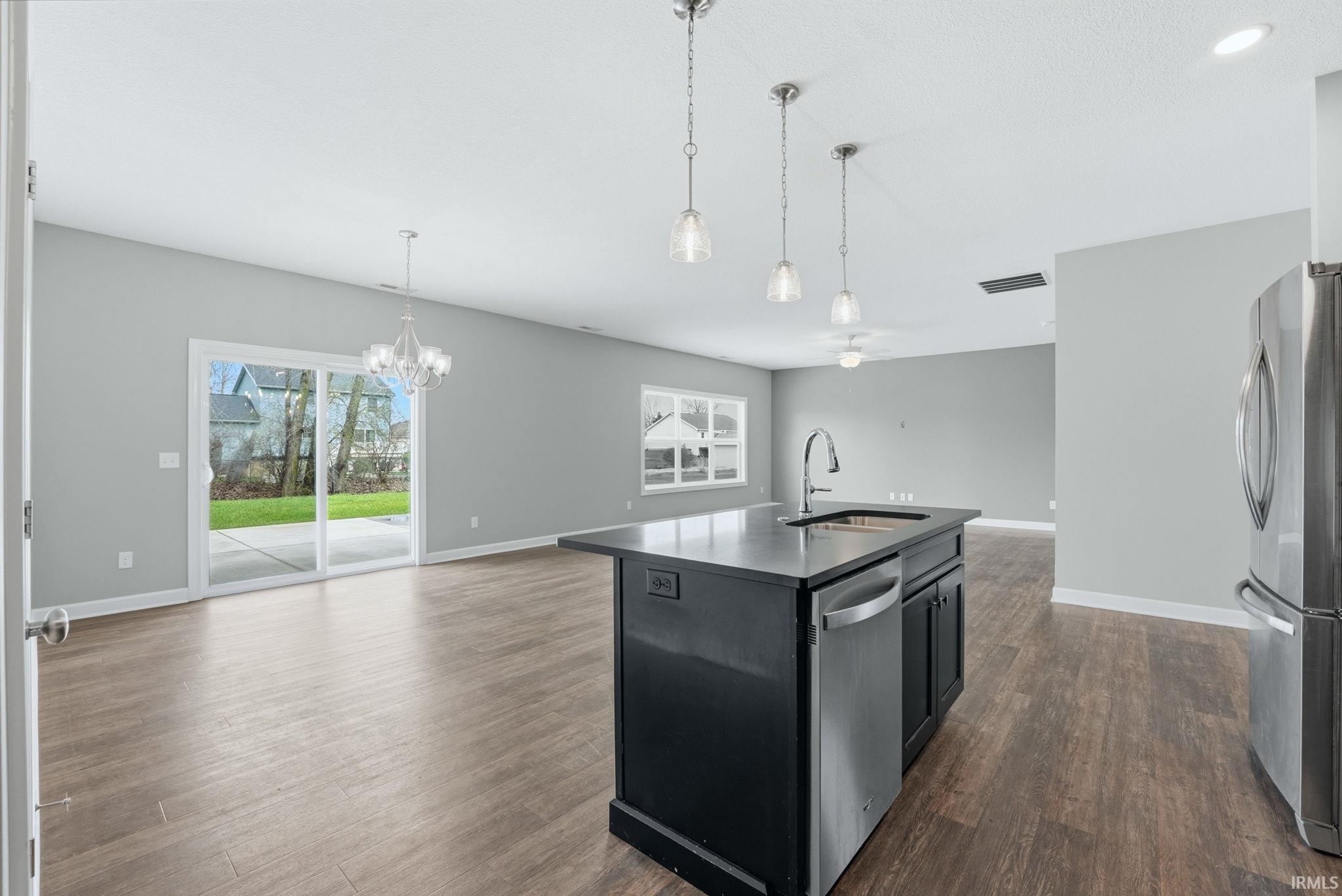 Kitchen featuring open floor plan, stainless steel appliances, a kitchen island with sink, dark wood finished floors, and plenty of natural light