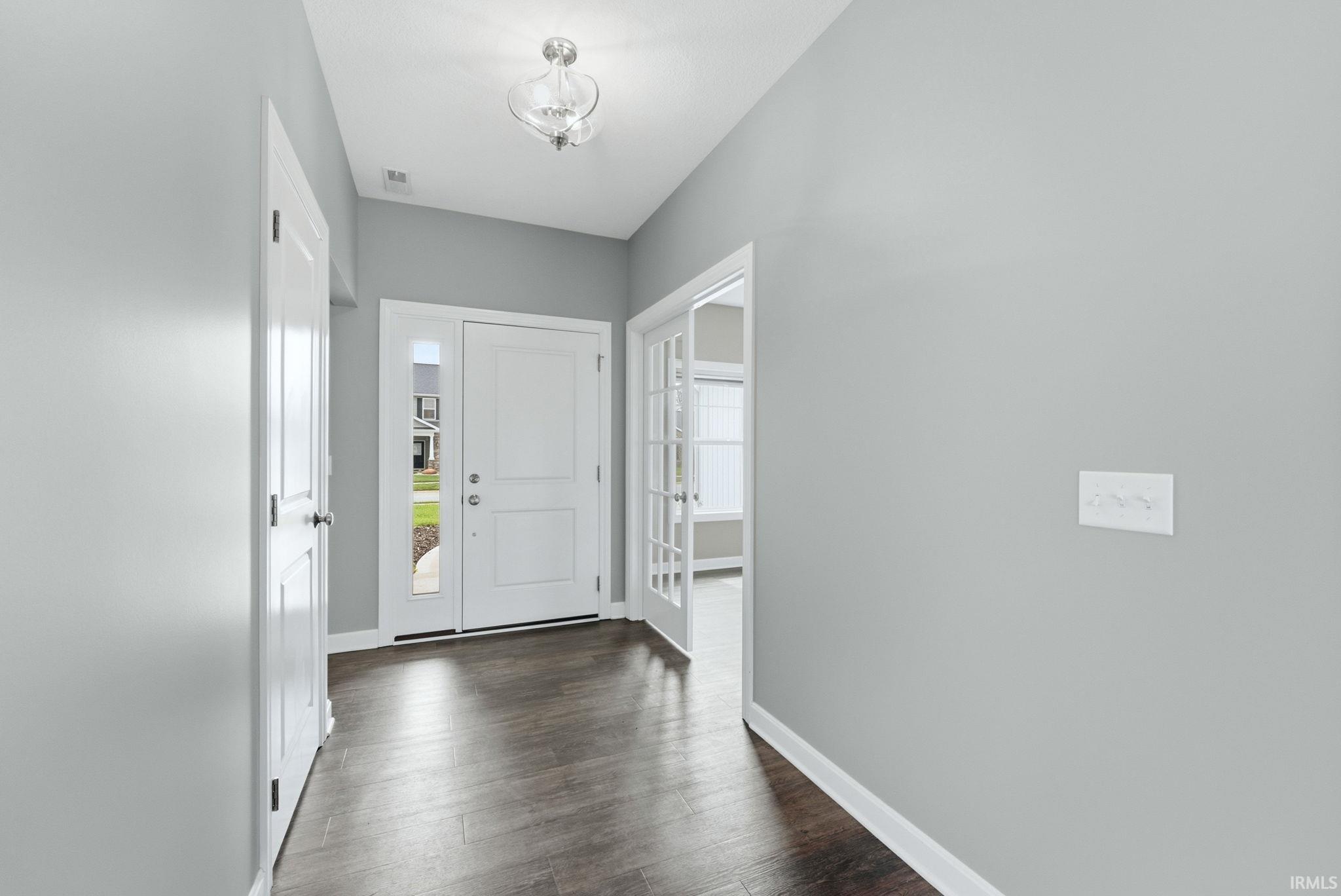 Entrance foyer with baseboards and dark wood-style flooring