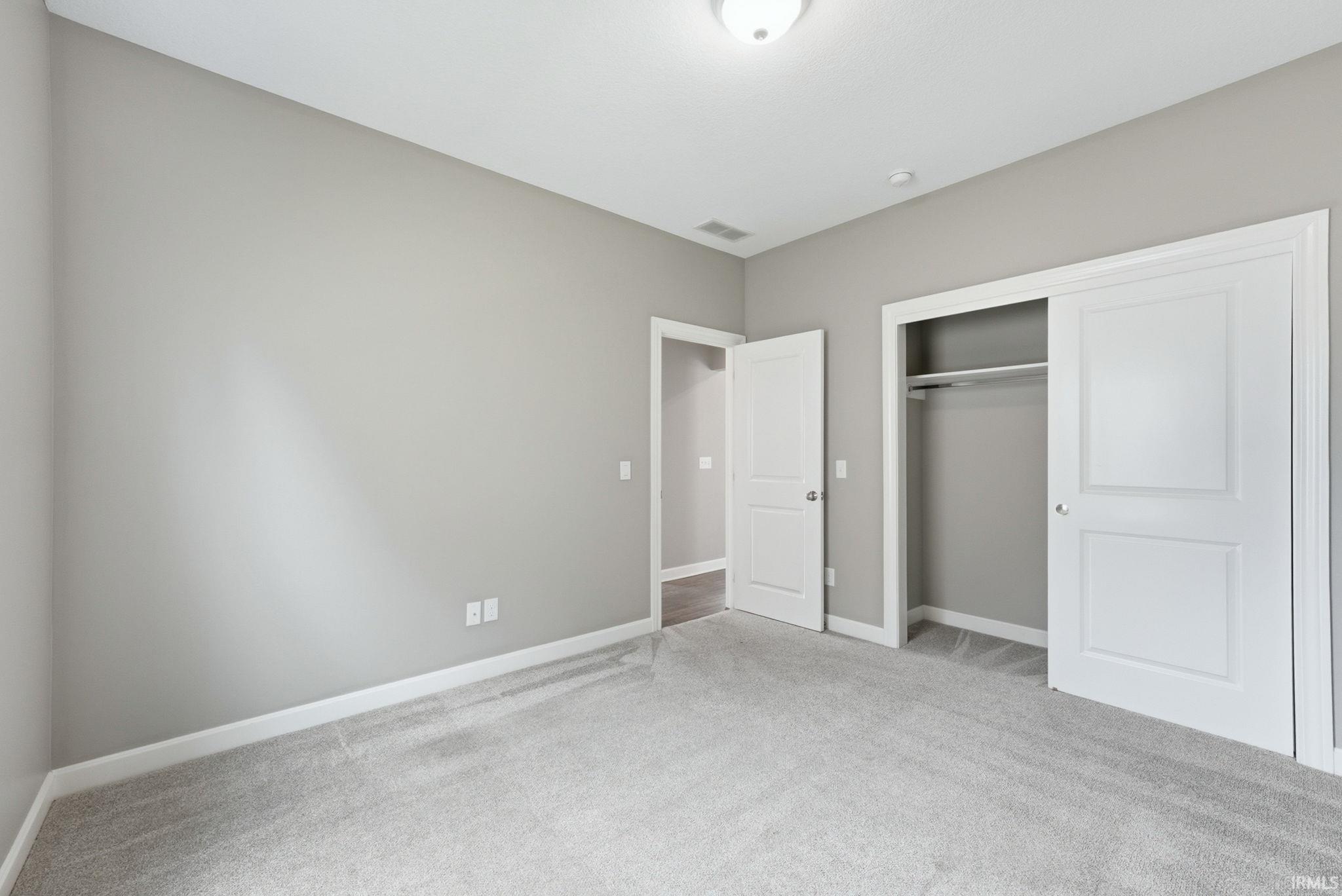 Unfurnished bedroom with light colored carpet and a closet