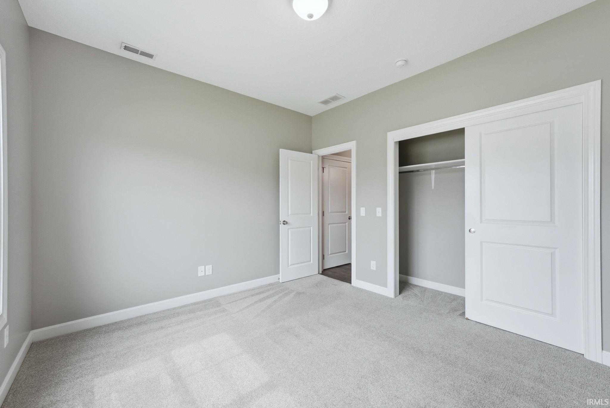 Unfurnished bedroom with light carpet and a closet