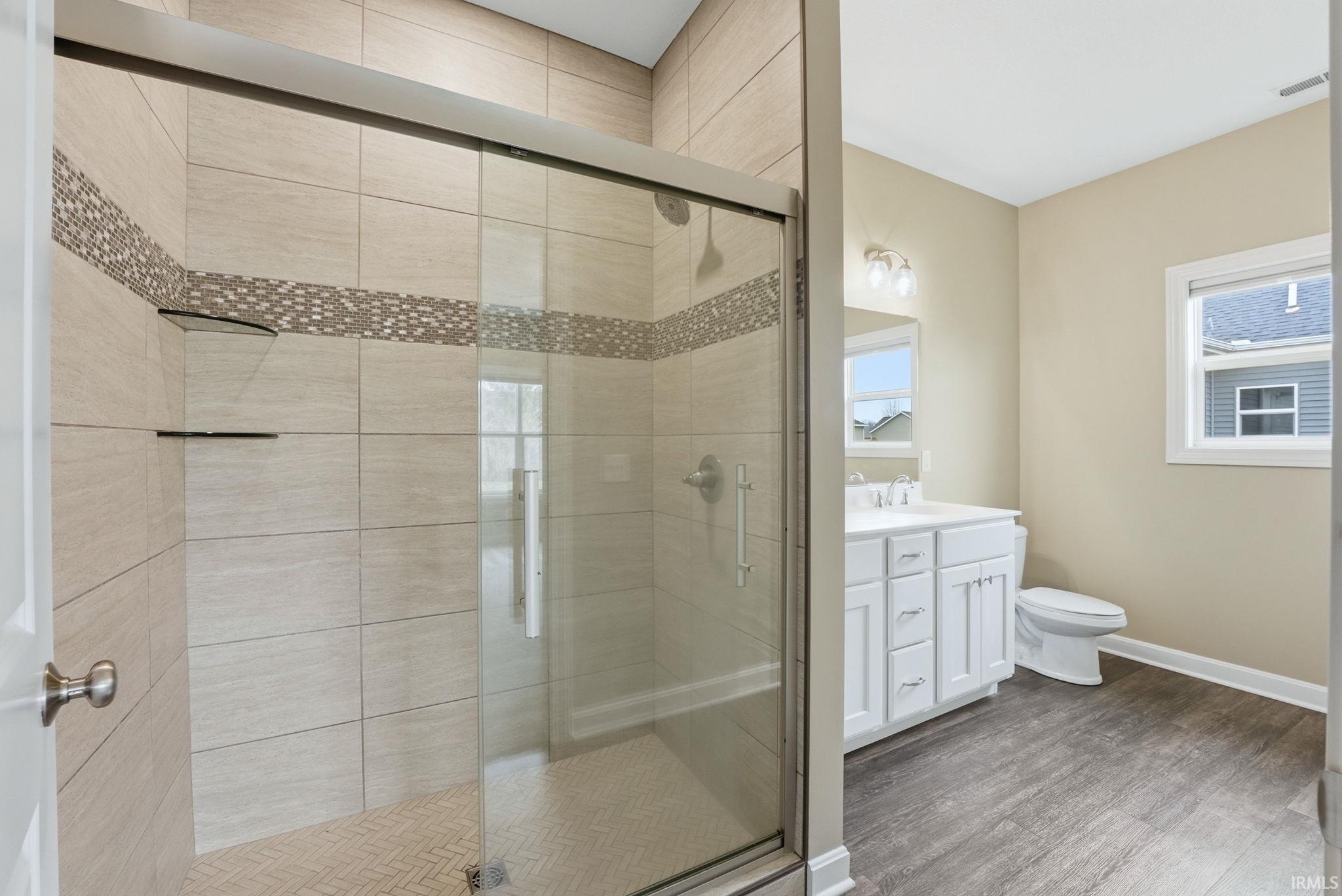 Bathroom featuring vanity, a stall shower, and light wood-style floors