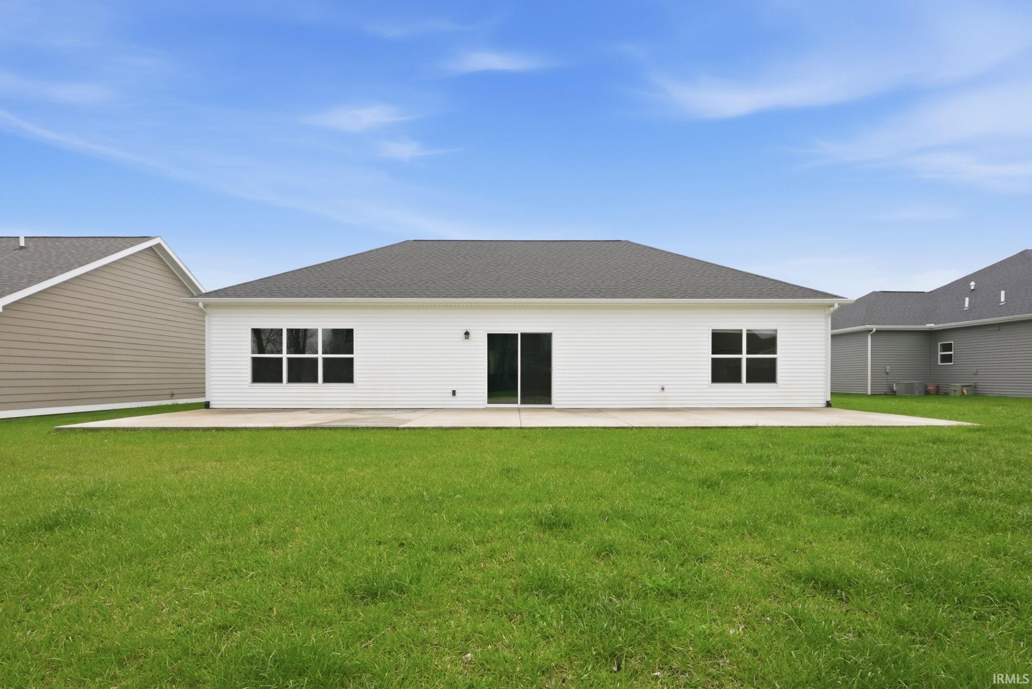 Back of property featuring a yard, a shingled roof, and a patio area