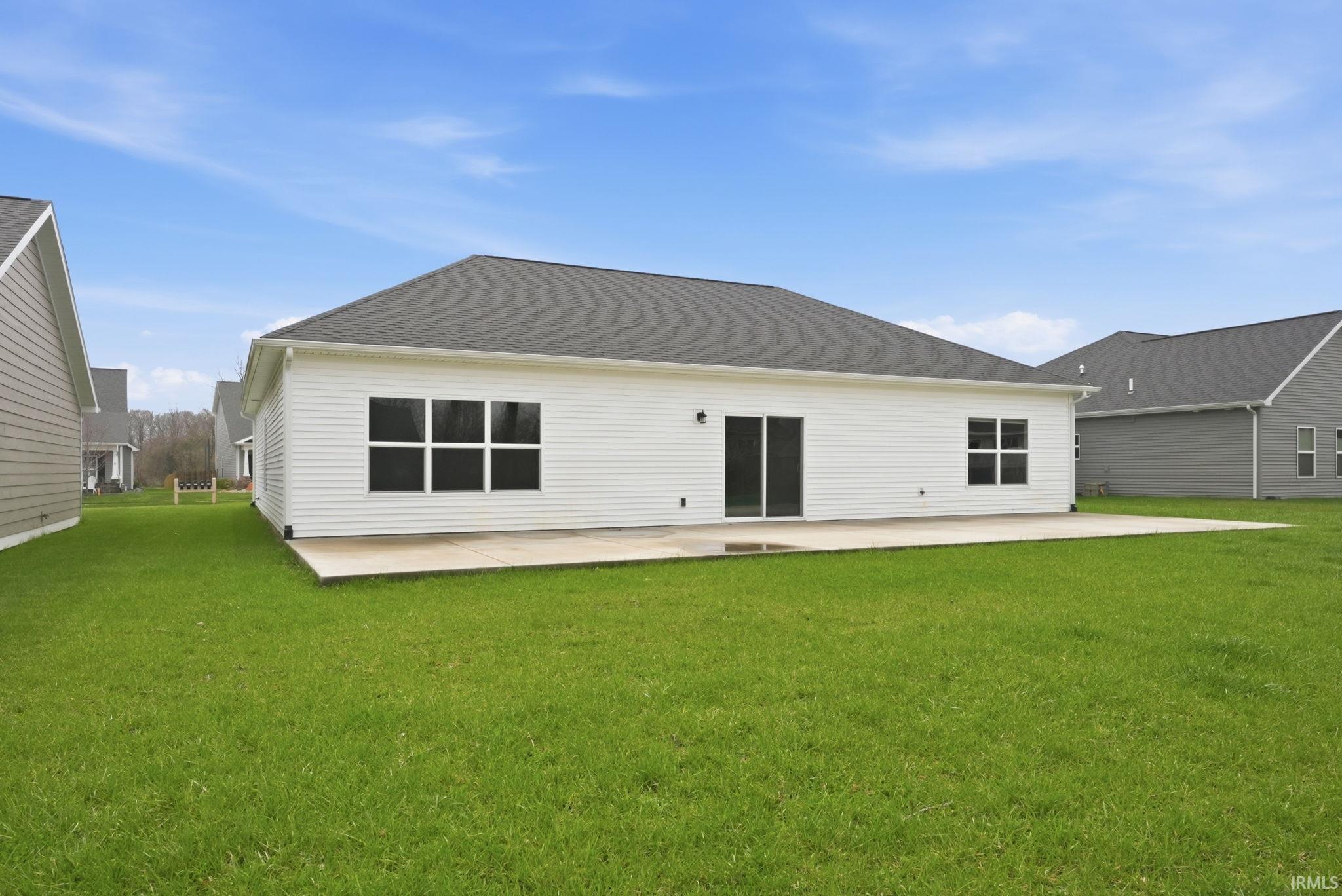 View of front of house with board and batten siding, an attached garage, concrete driveway, brick siding, and a front yard
