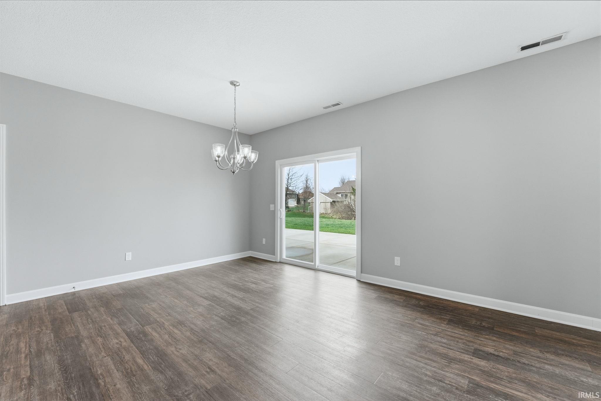 Empty room featuring hanging lights and dark wood-style flooring