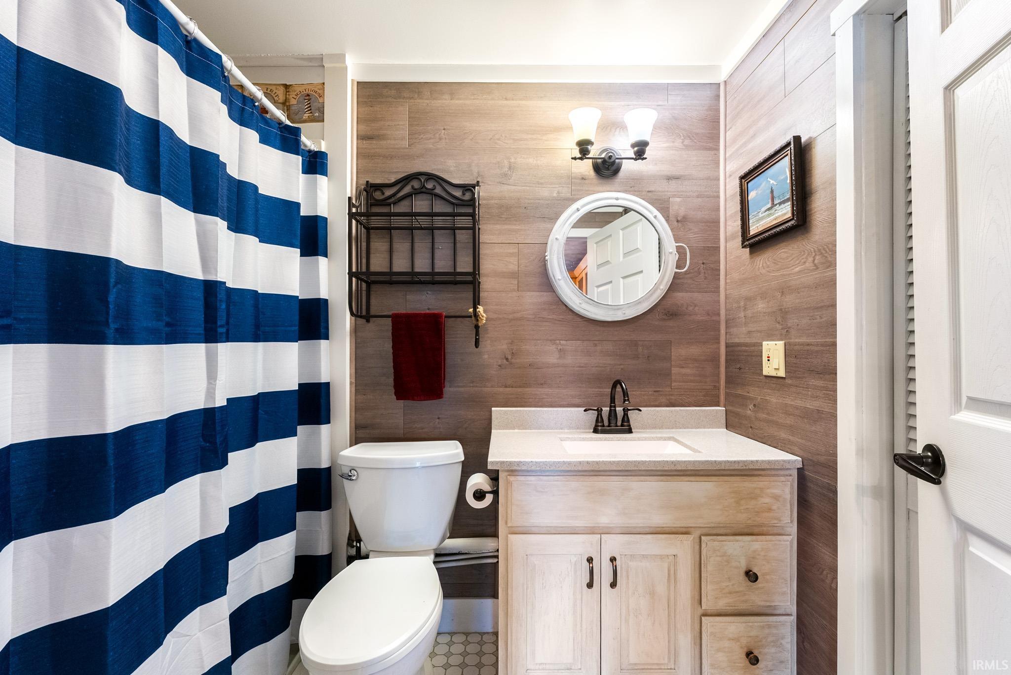 Bathroom with vanity, a shower with shower curtain, and wooden walls