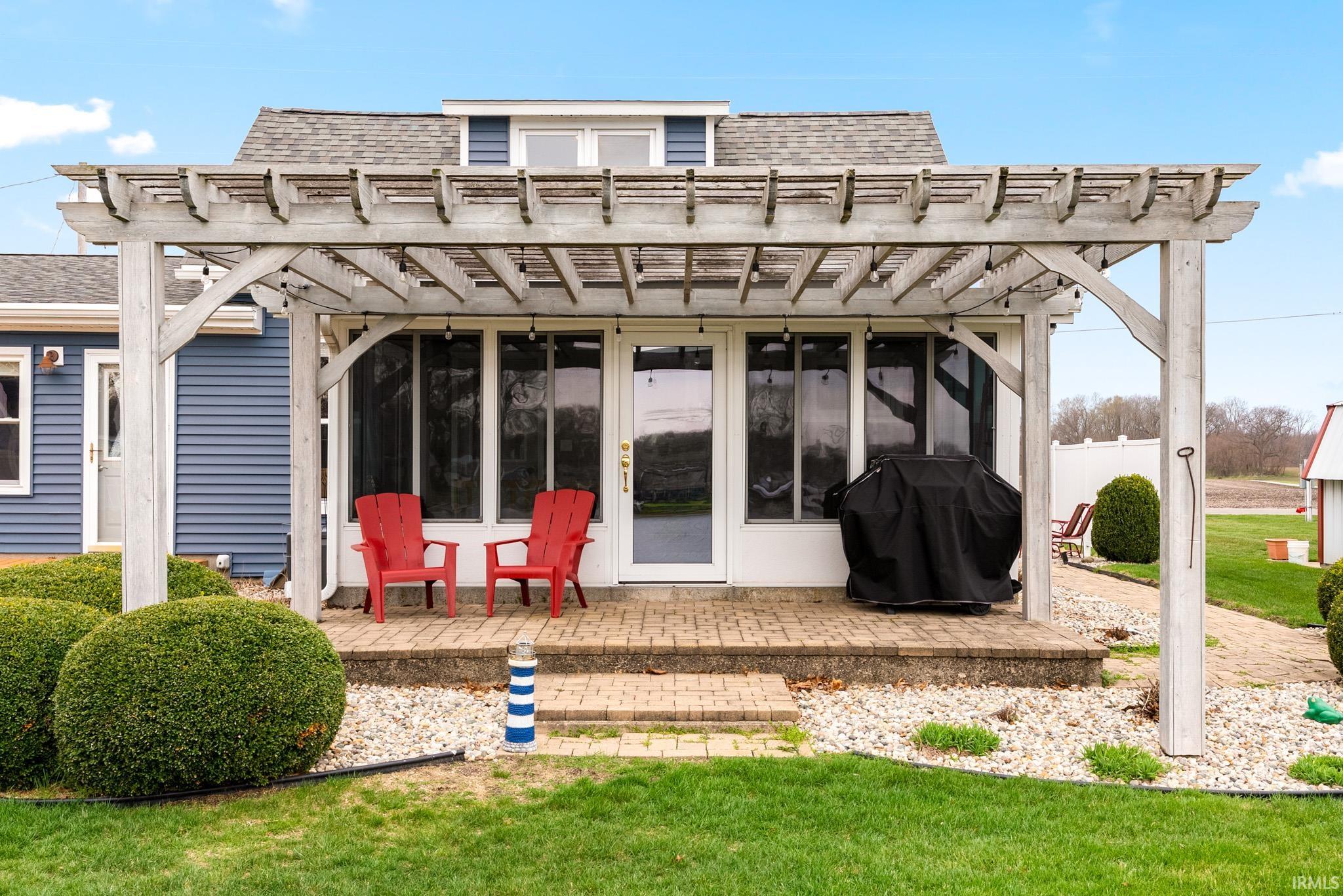 Rear view of house with a shingled roof, a yard, a pergola, and a patio area