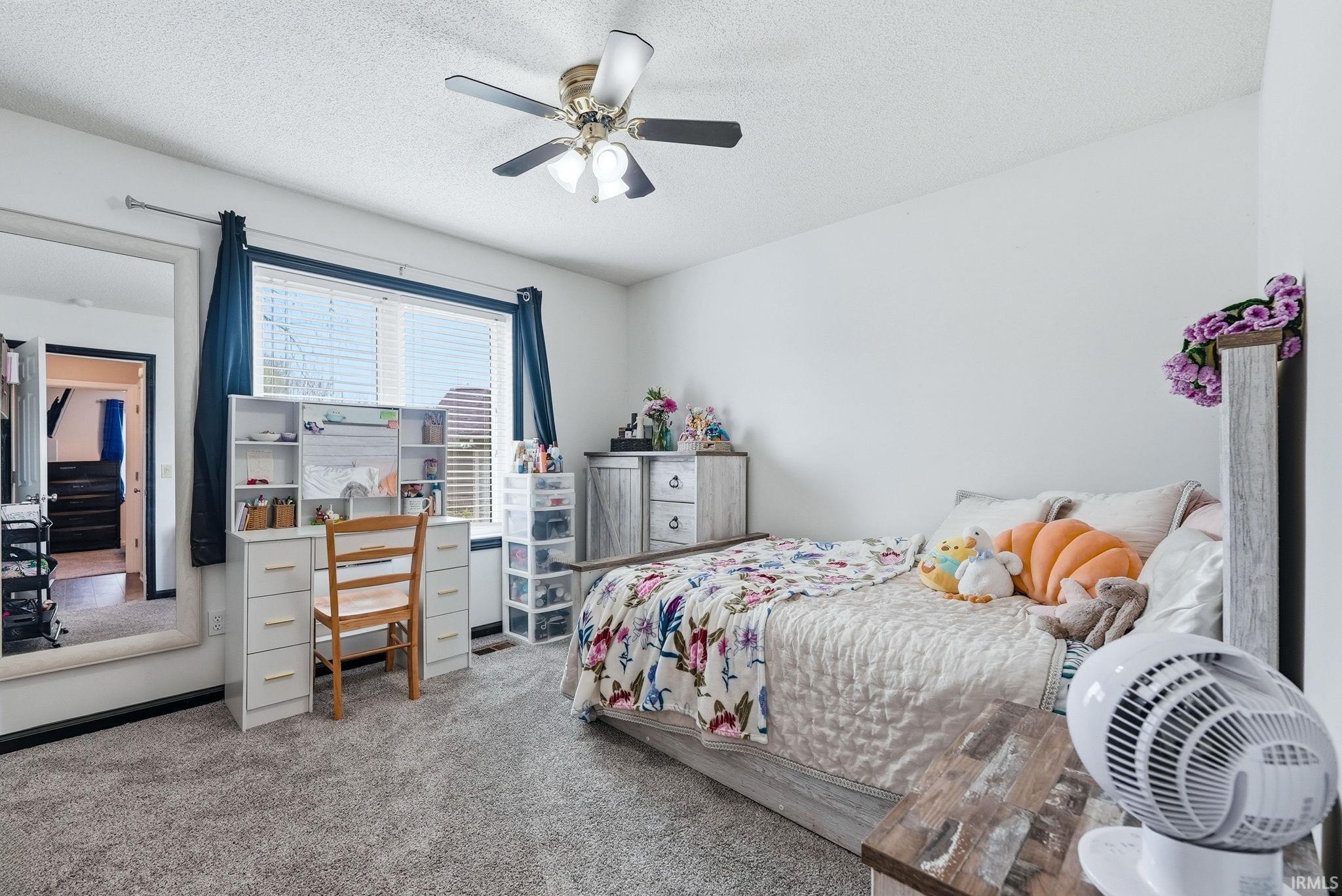 Bedroom featuring light colored carpet, a textured ceiling, and ceiling fan