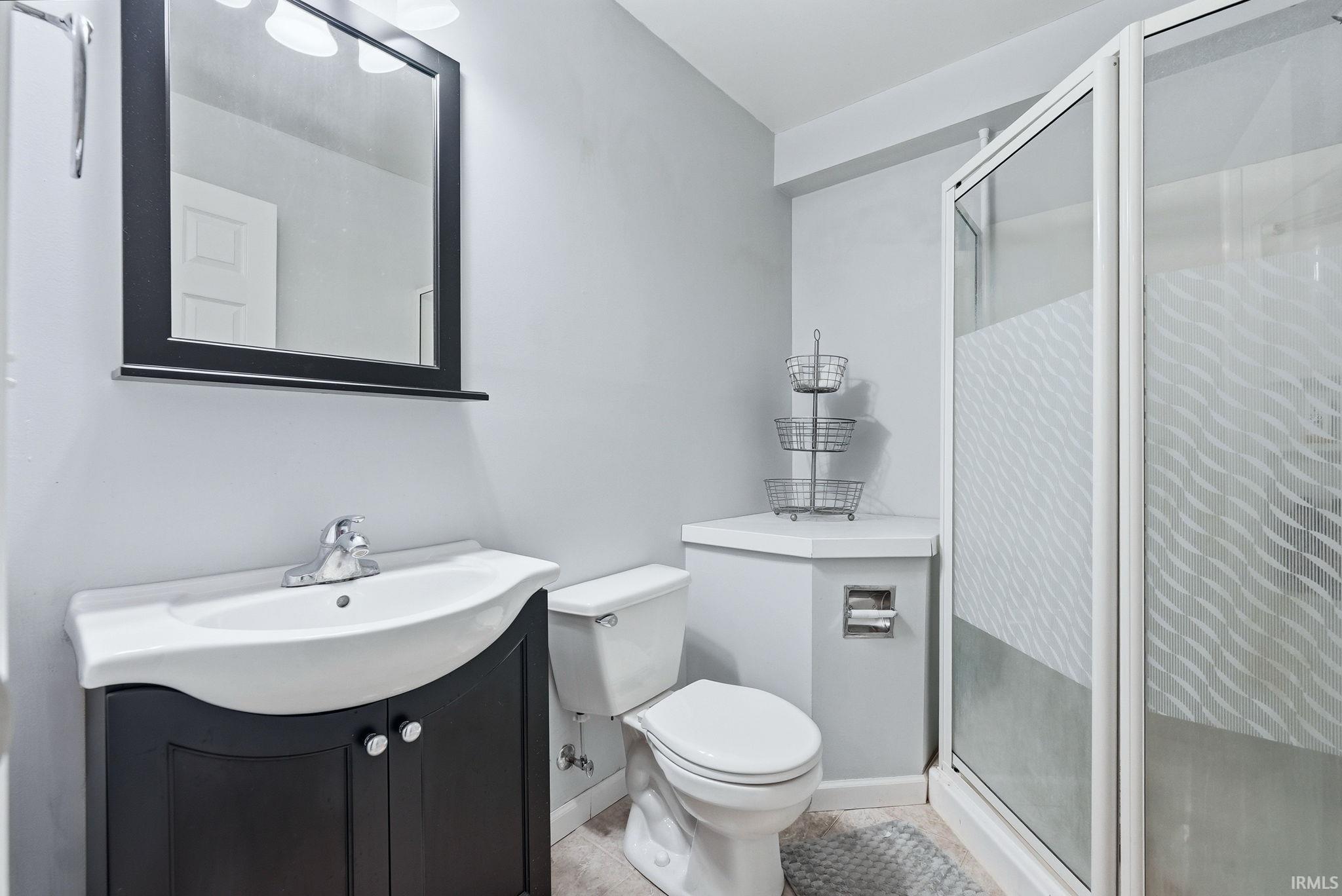 Full bath with vanity, a shower stall, and light tile patterned floors