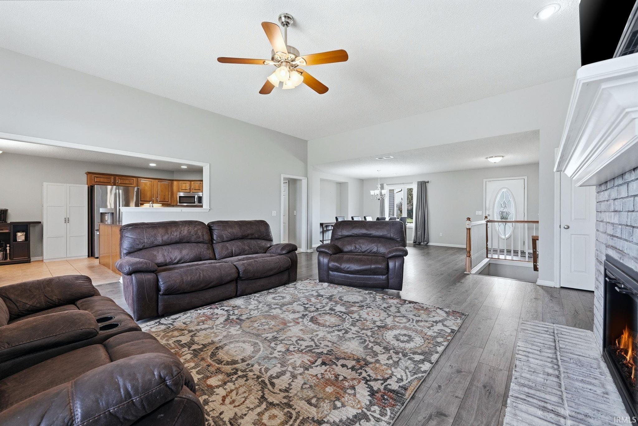 Living room with a brick fireplace, a ceiling fan, recessed lighting, and light wood-type flooring