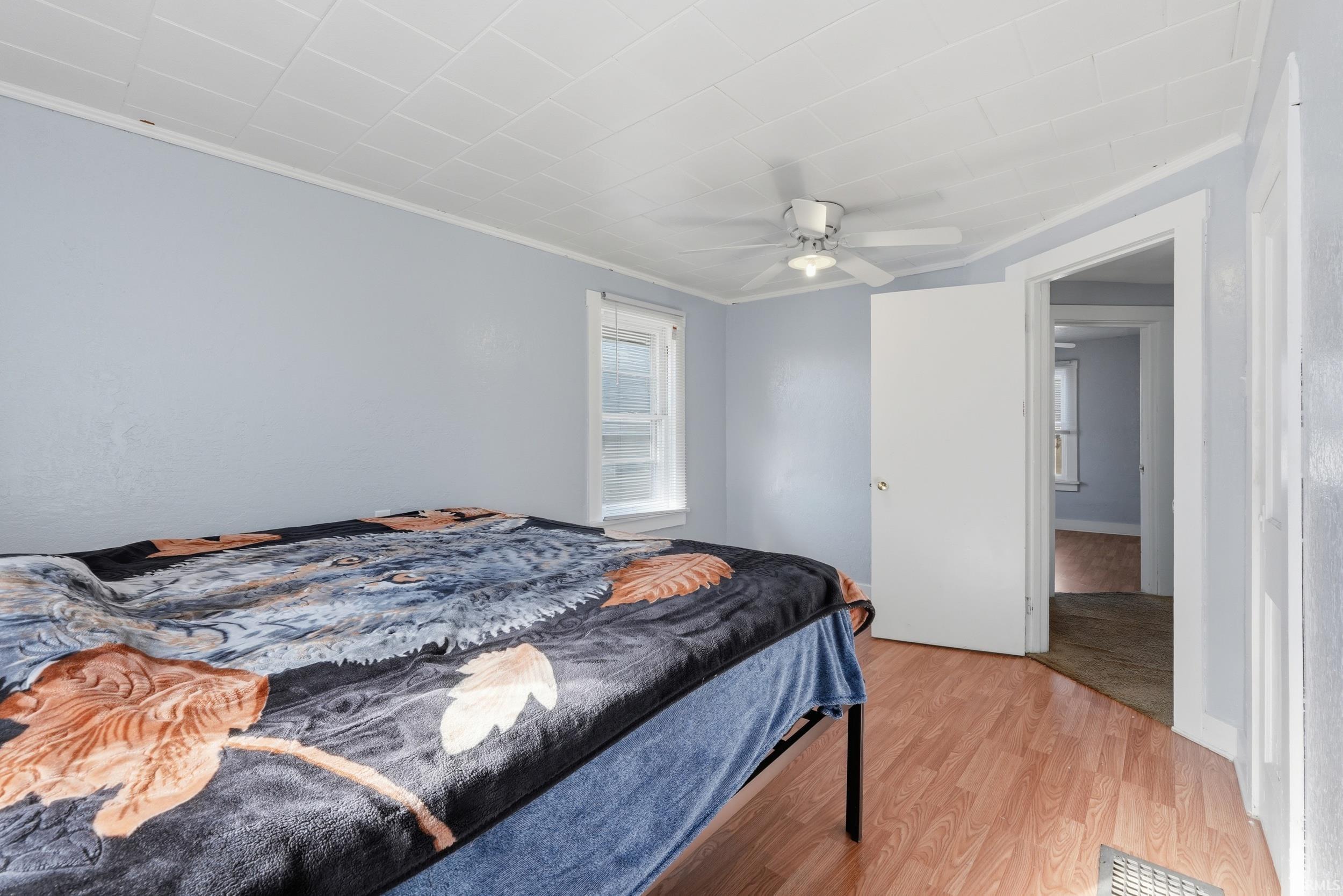 Bedroom featuring light wood-type flooring, ceiling fan, and ornamental molding