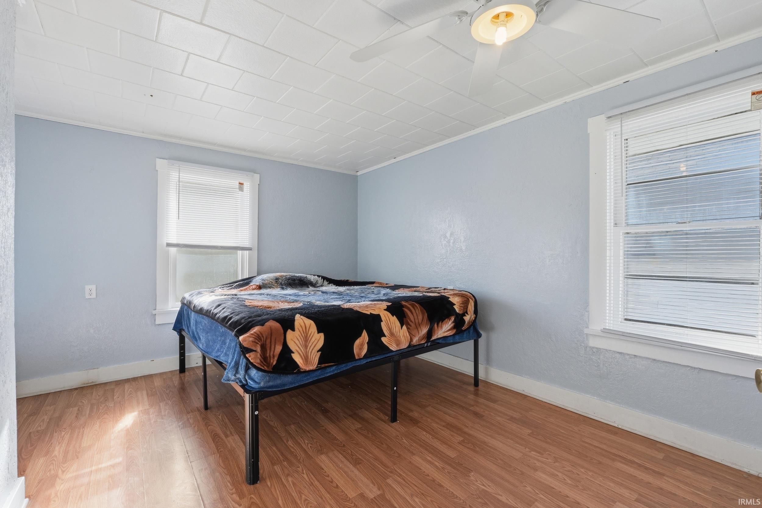 Bedroom featuring crown molding, wood finished floors, and a ceiling fan