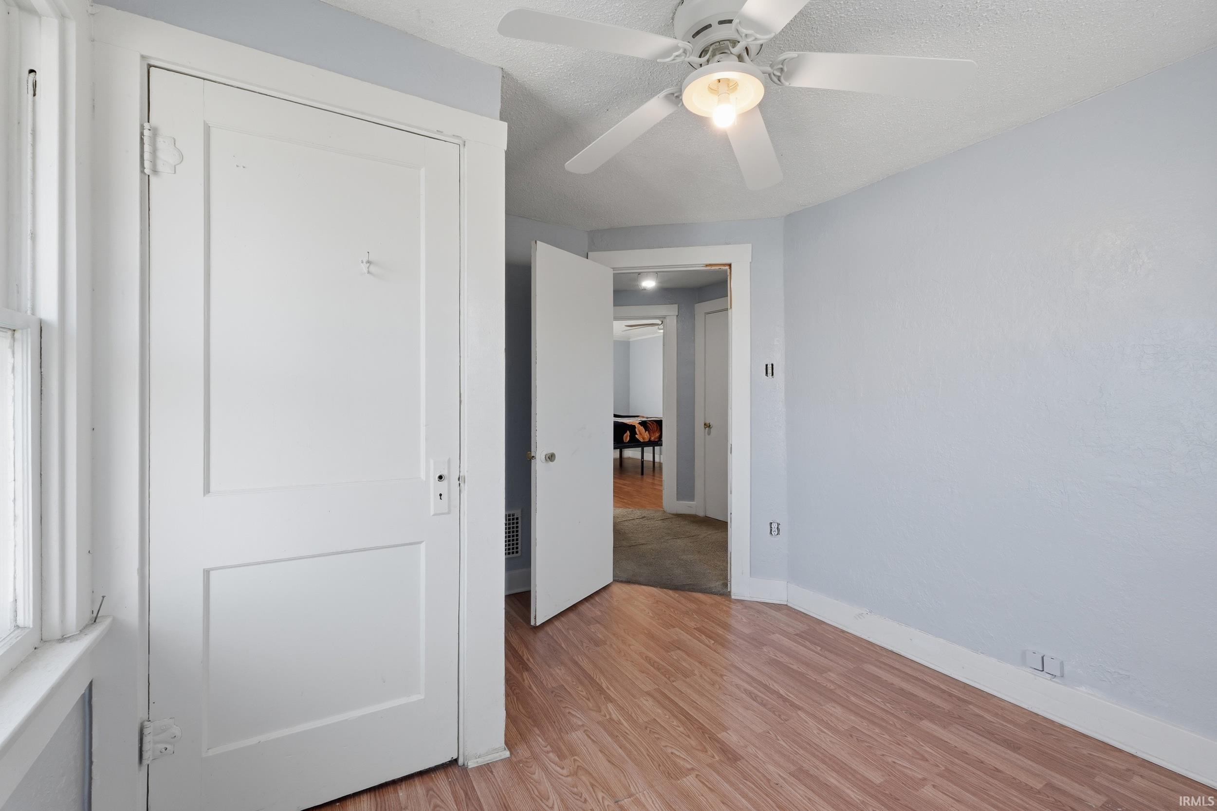 Unfurnished bedroom with light wood-style flooring, ceiling fan, and a textured ceiling